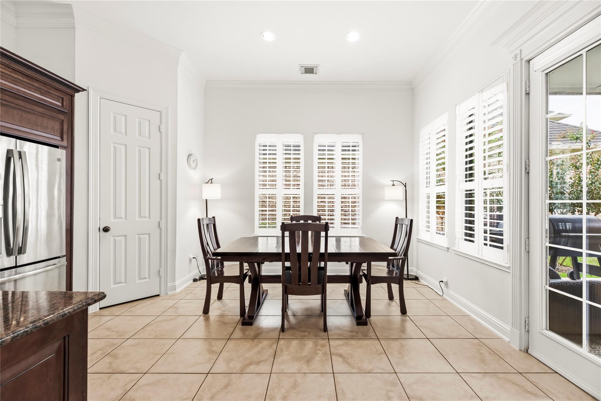 Dining area with dark wood table and chairs, plantation shutters, and patio doors.