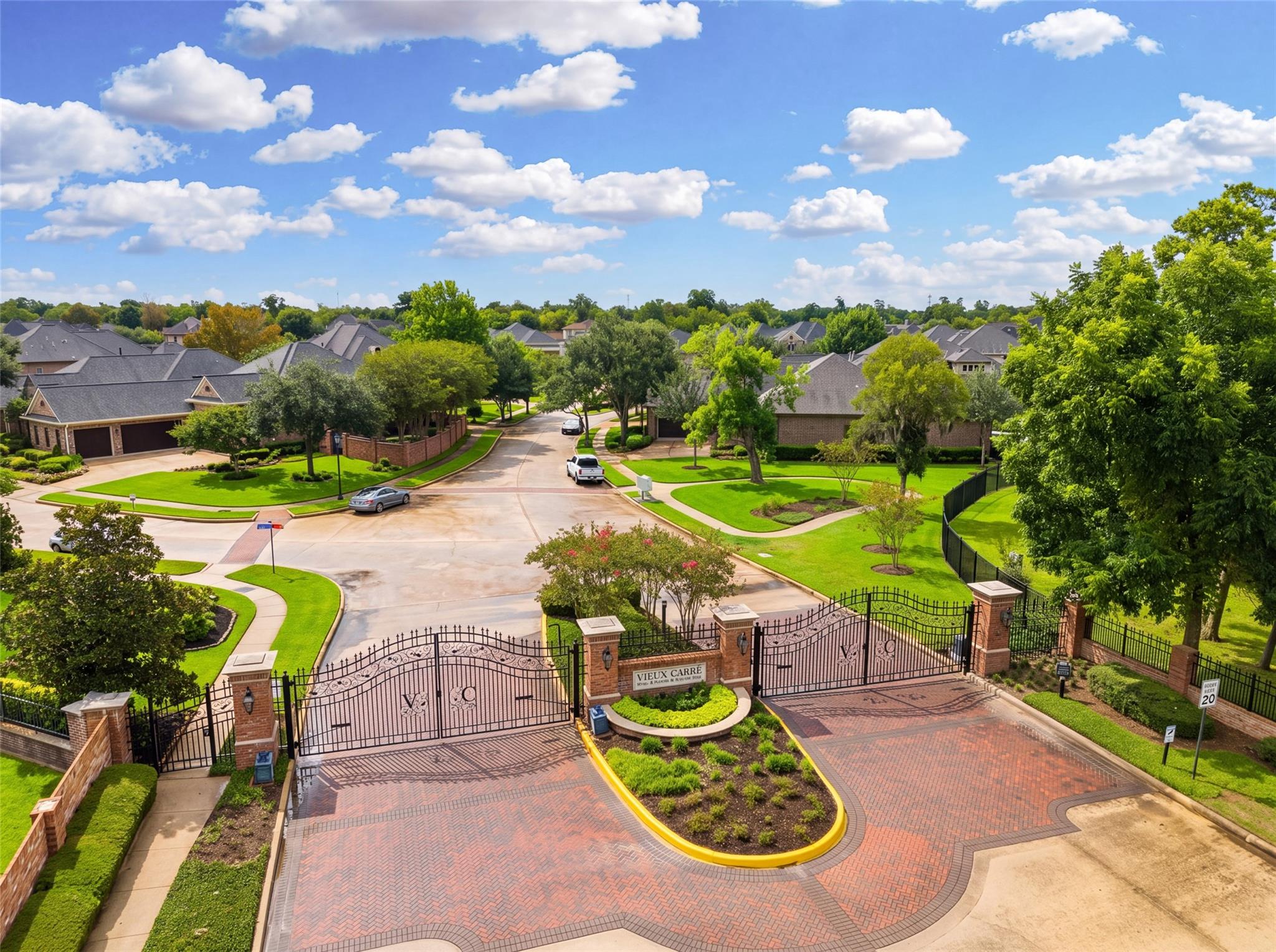 Gated Vieux Carre neighborhood entrance with brick-paved drive and landscaped homes beyond.