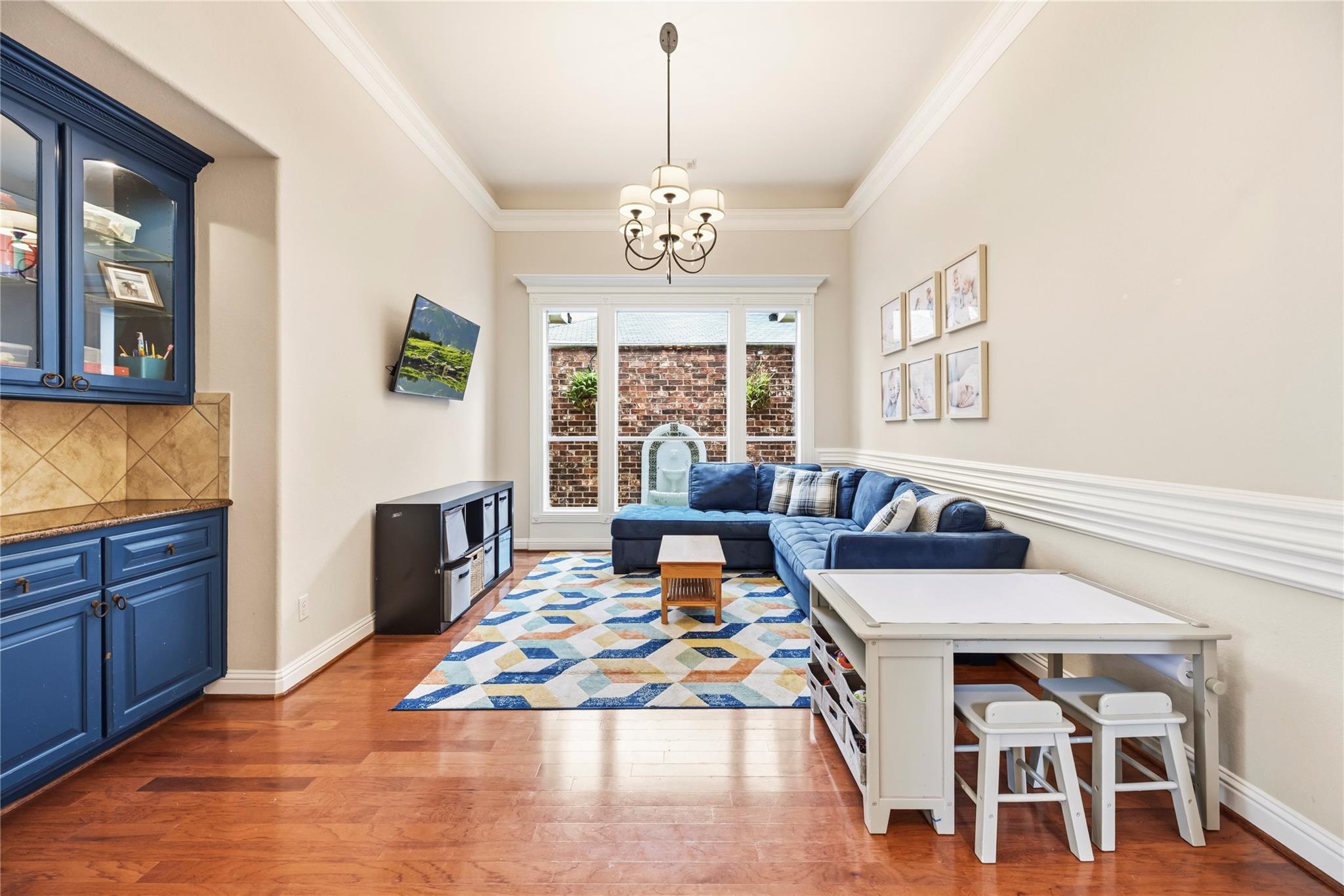 Family room with blue sectional, built-in cabinetry, geometric rug, and white activity table.