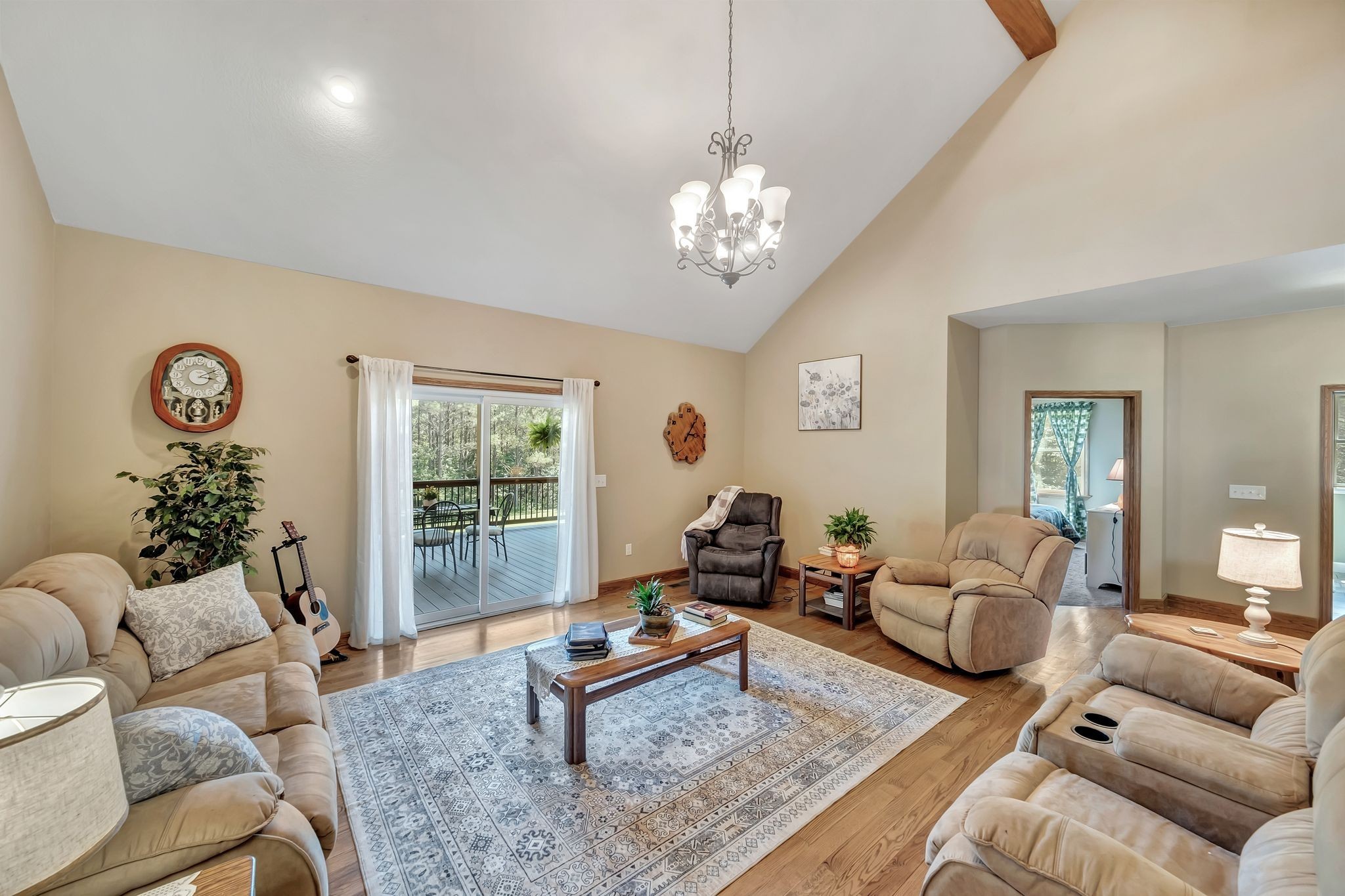 Furnished living room with vaulted ceiling and sliding doors opening onto a deck