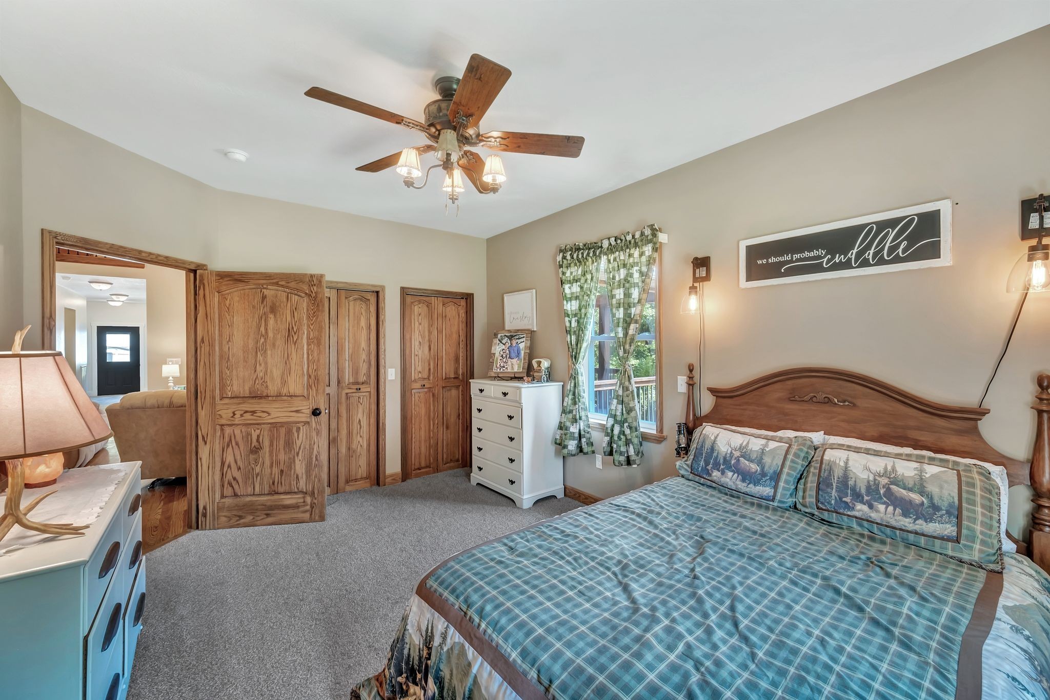 Bedroom with a large wooden bed, blue plaid bedding, and matching wood doors.