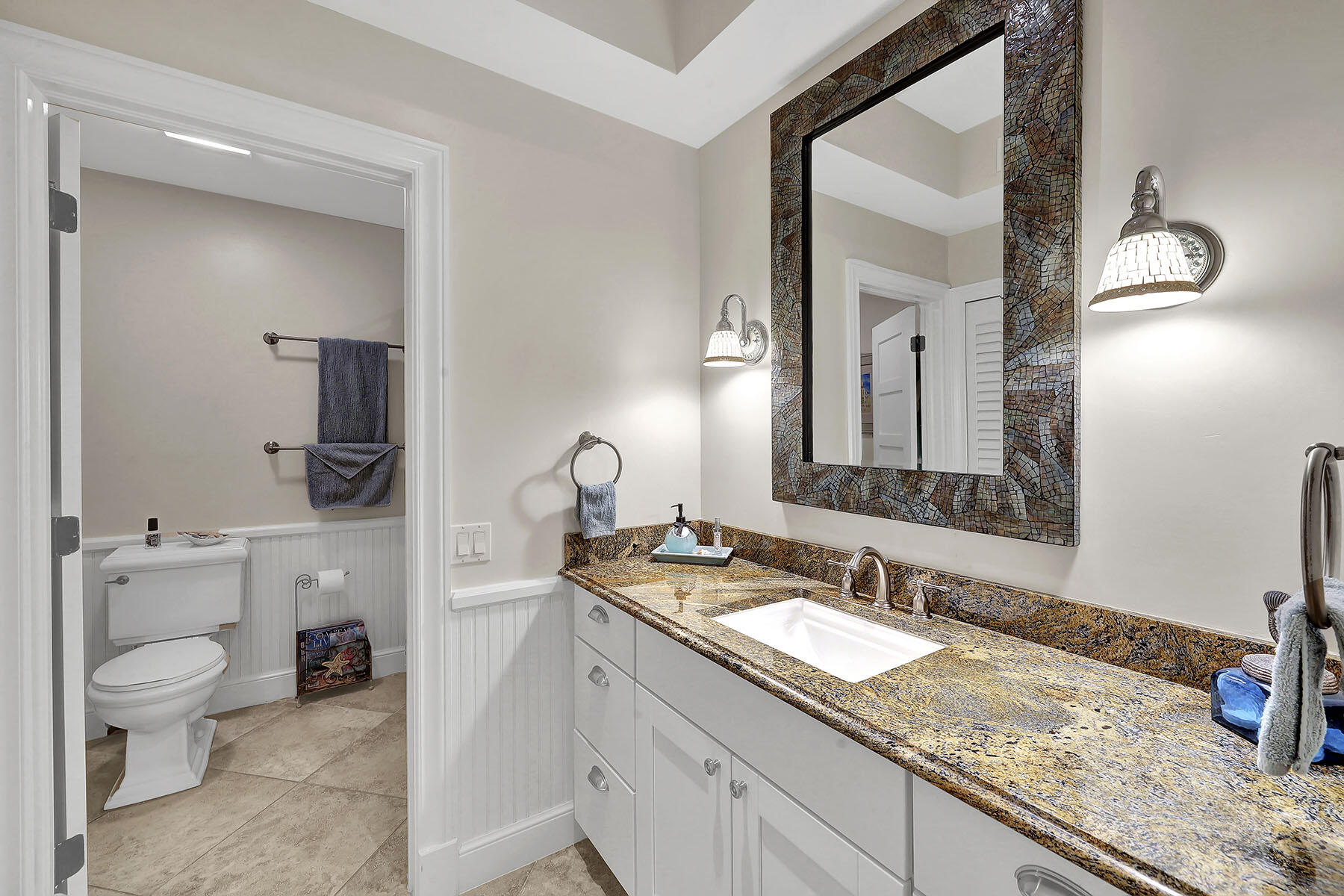 Bathroom with a granite vanity, undermount sink, and large mosaic-framed mirror.