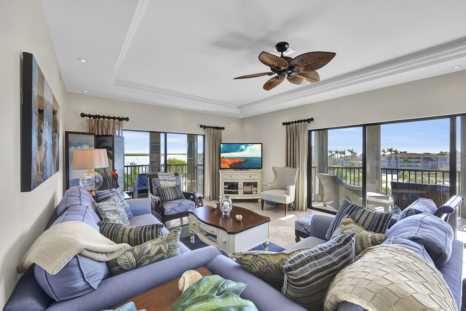 Furnished living room with blue sofas and sliding doors overlooking water.