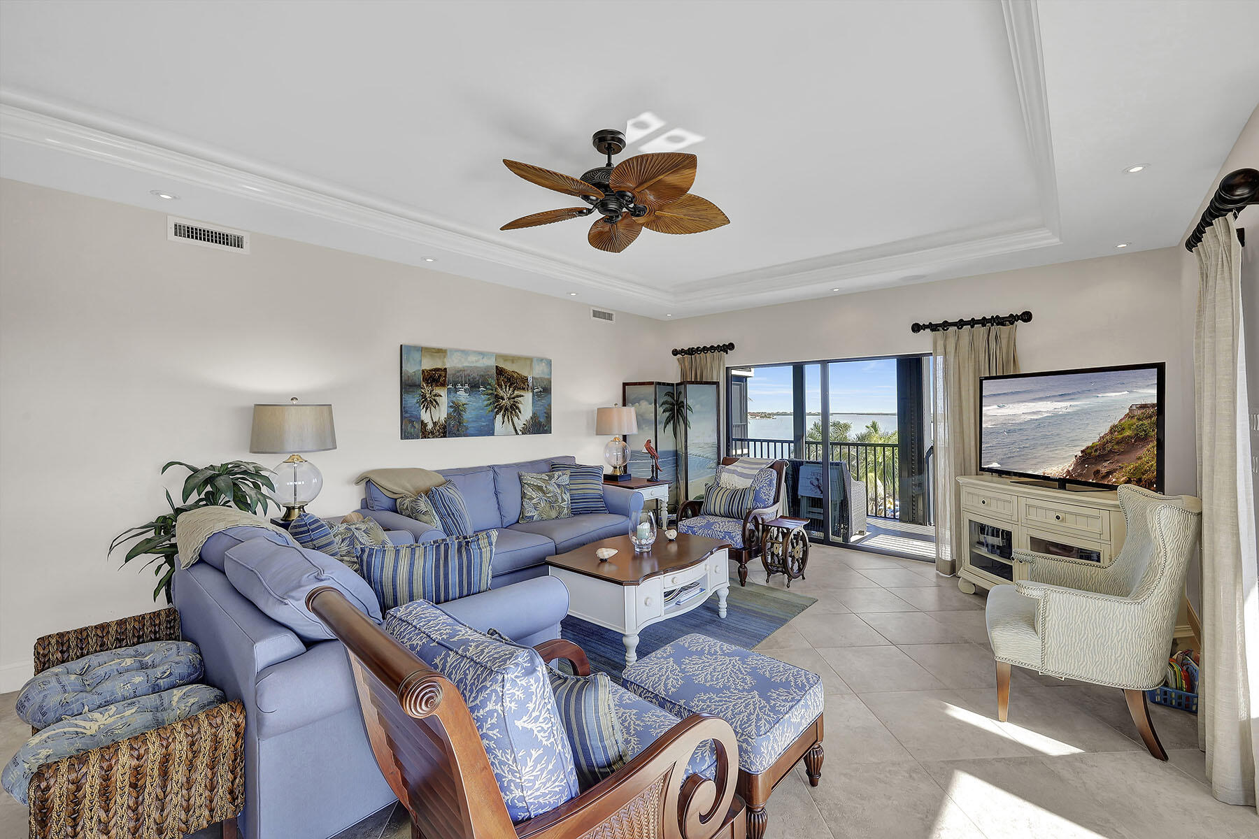 Living room with blue sectional seating and a balcony overlooking the water.