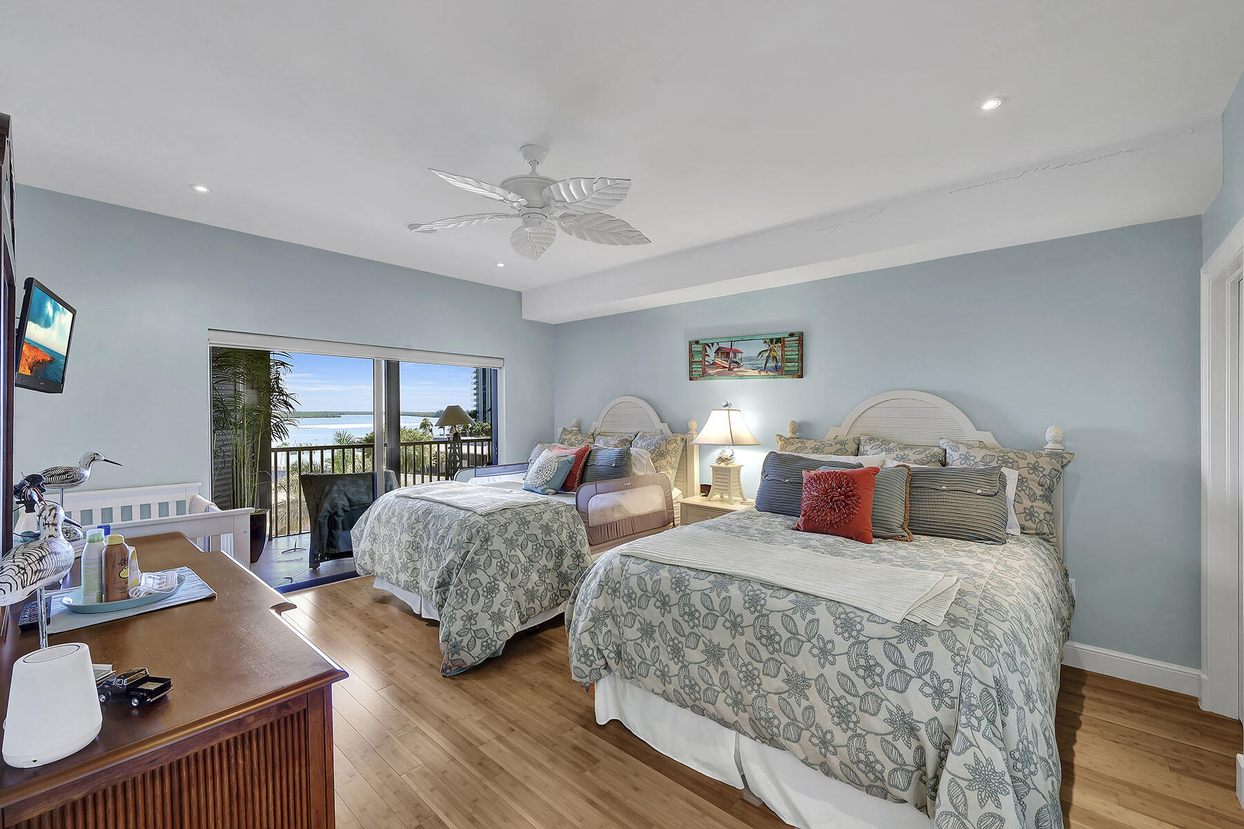 Bedroom with two beds and sliding doors opening to a balcony overlooking the water.