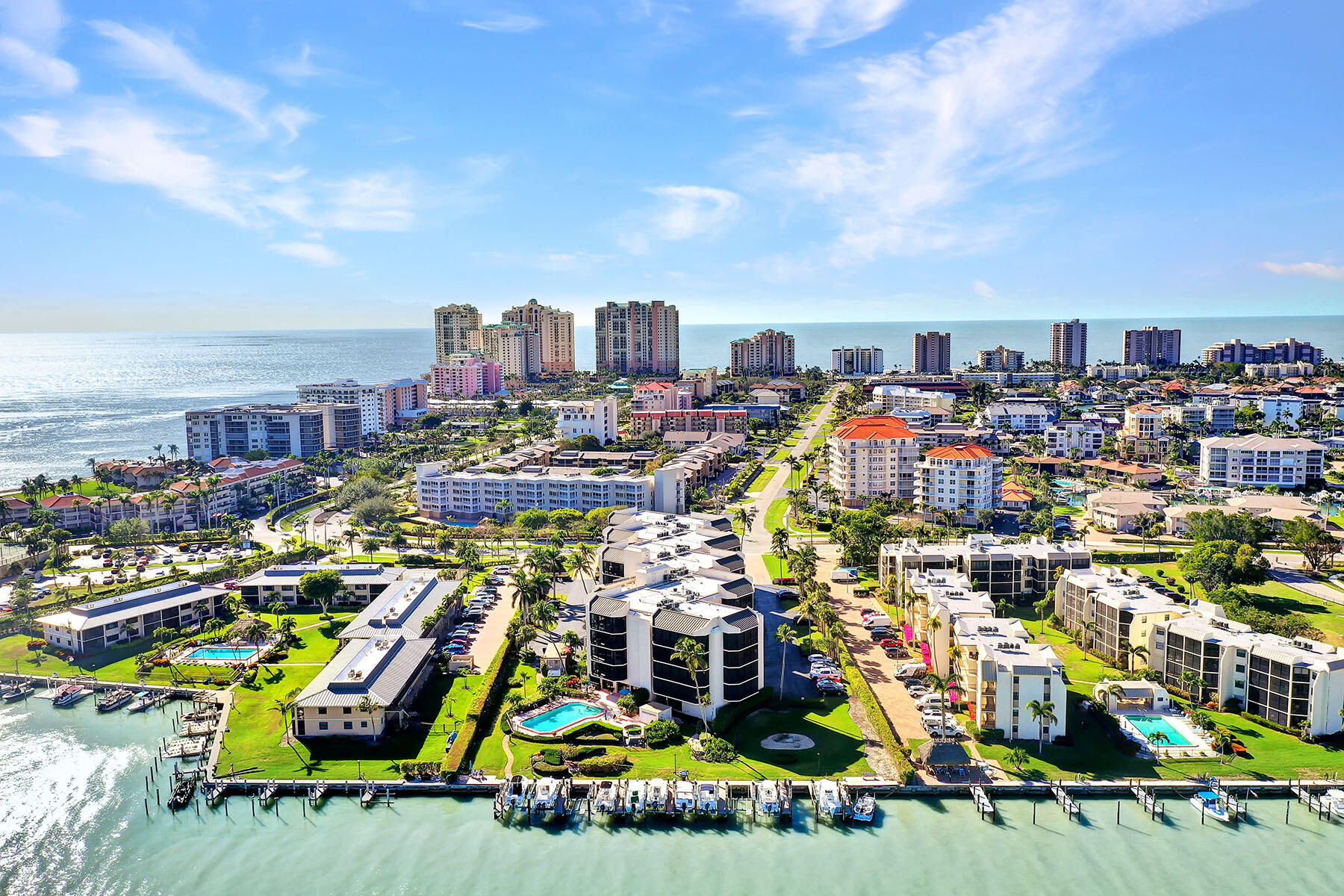 Aerial view of Marco Island condos and homes between the Gulf shoreline and a waterfront marina.