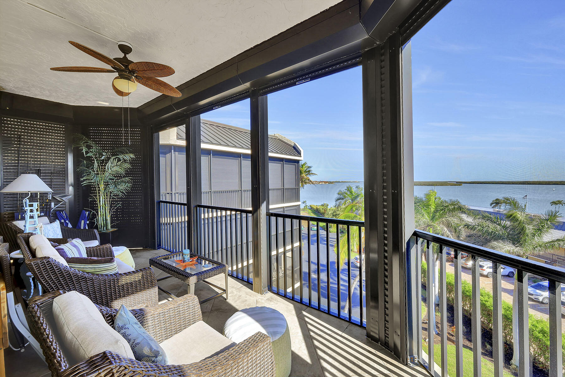 Screened balcony with wicker seating and a wide water view.