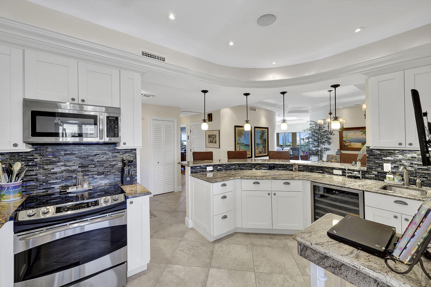 Kitchen with white cabinetry, granite counters, dark mosaic backsplash, and a curved breakfast bar.