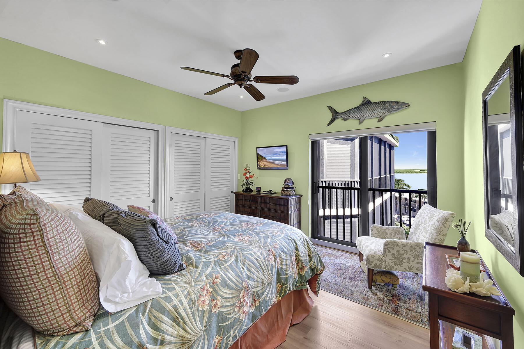 Bedroom with a floral bedspread and balcony doors overlooking the water.