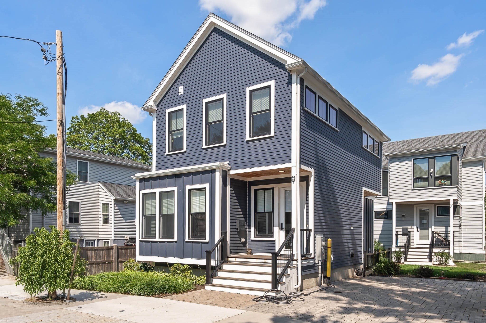 Dark blue two-story home with white trim, a covered entry, and front steps.