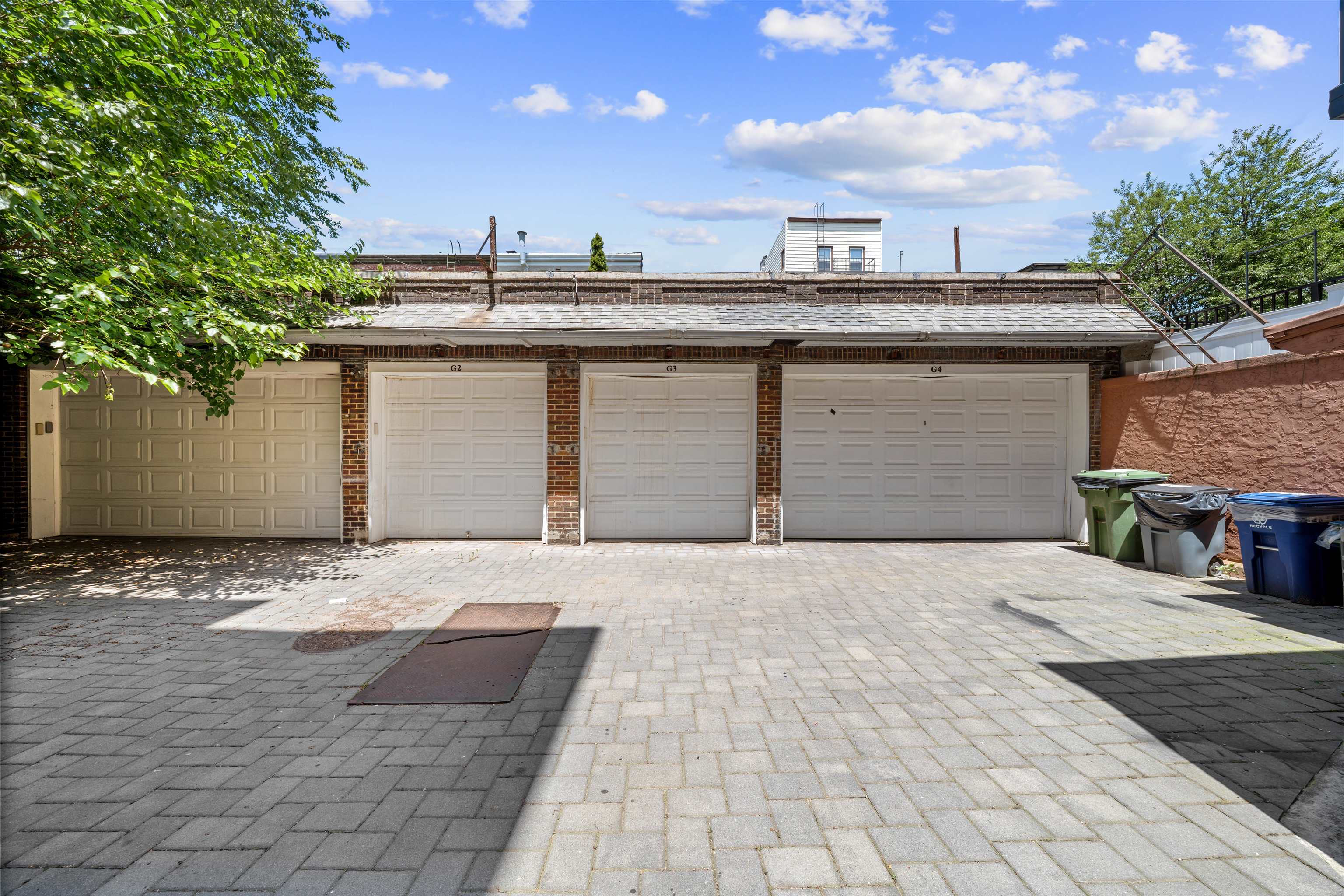 Three brick garage bays labeled G2, G3, and G4 beside a paved courtyard.
