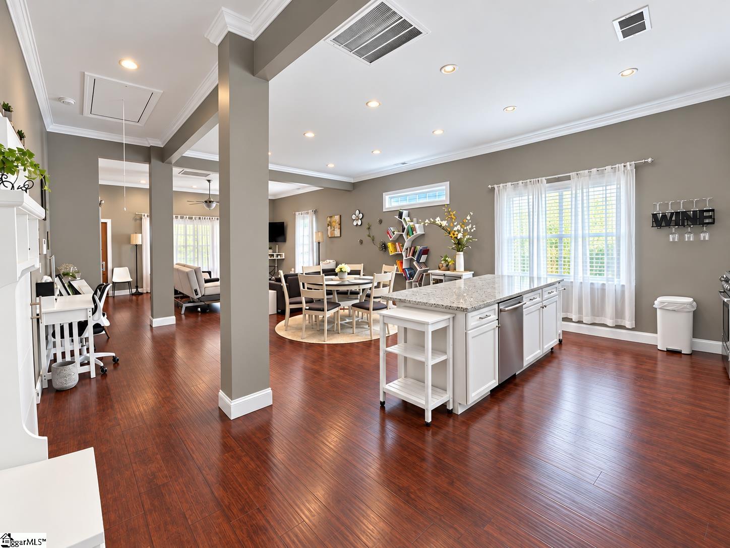Open-plan kitchen and dining area with a stone-topped island, dark hardwood floors, and adjoining living space.