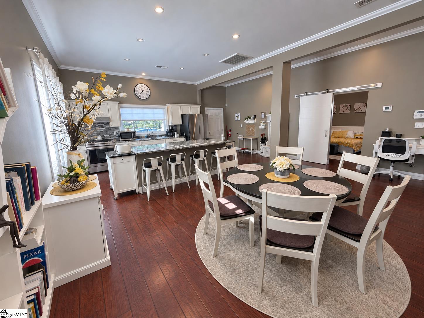 Open kitchen and dining area with a large island, stainless steel appliances, and round table.