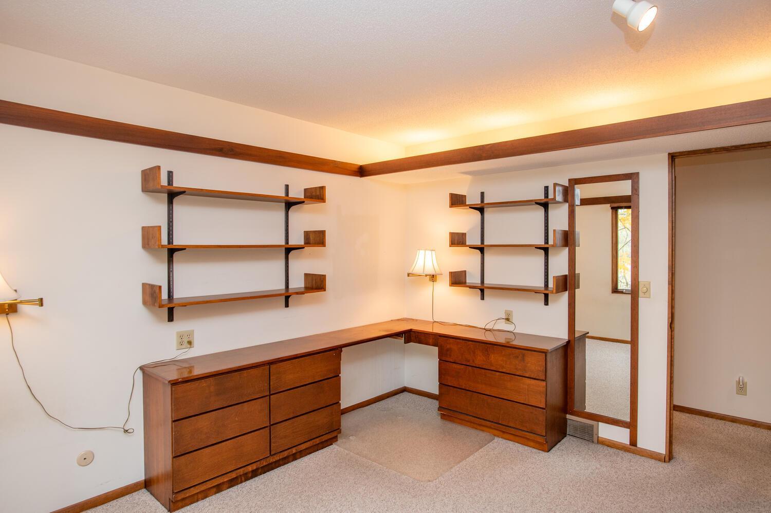 Home office with a built-in wooden desk and matching open shelves.