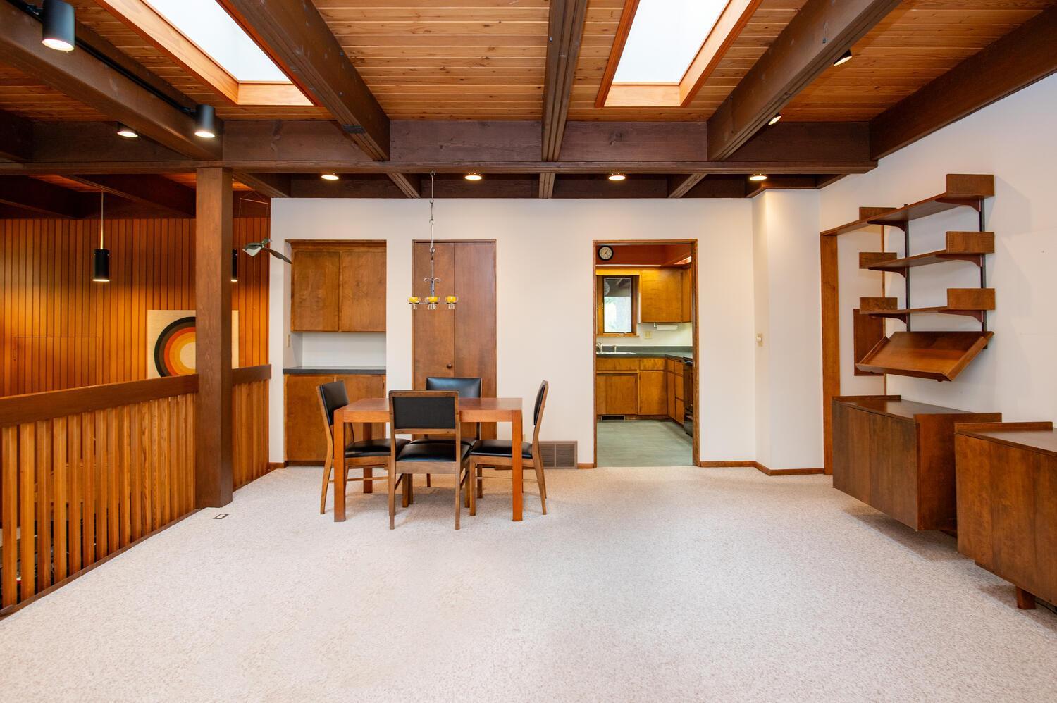 Dining area with exposed timber beams, skylights, and built-in wooden shelving.