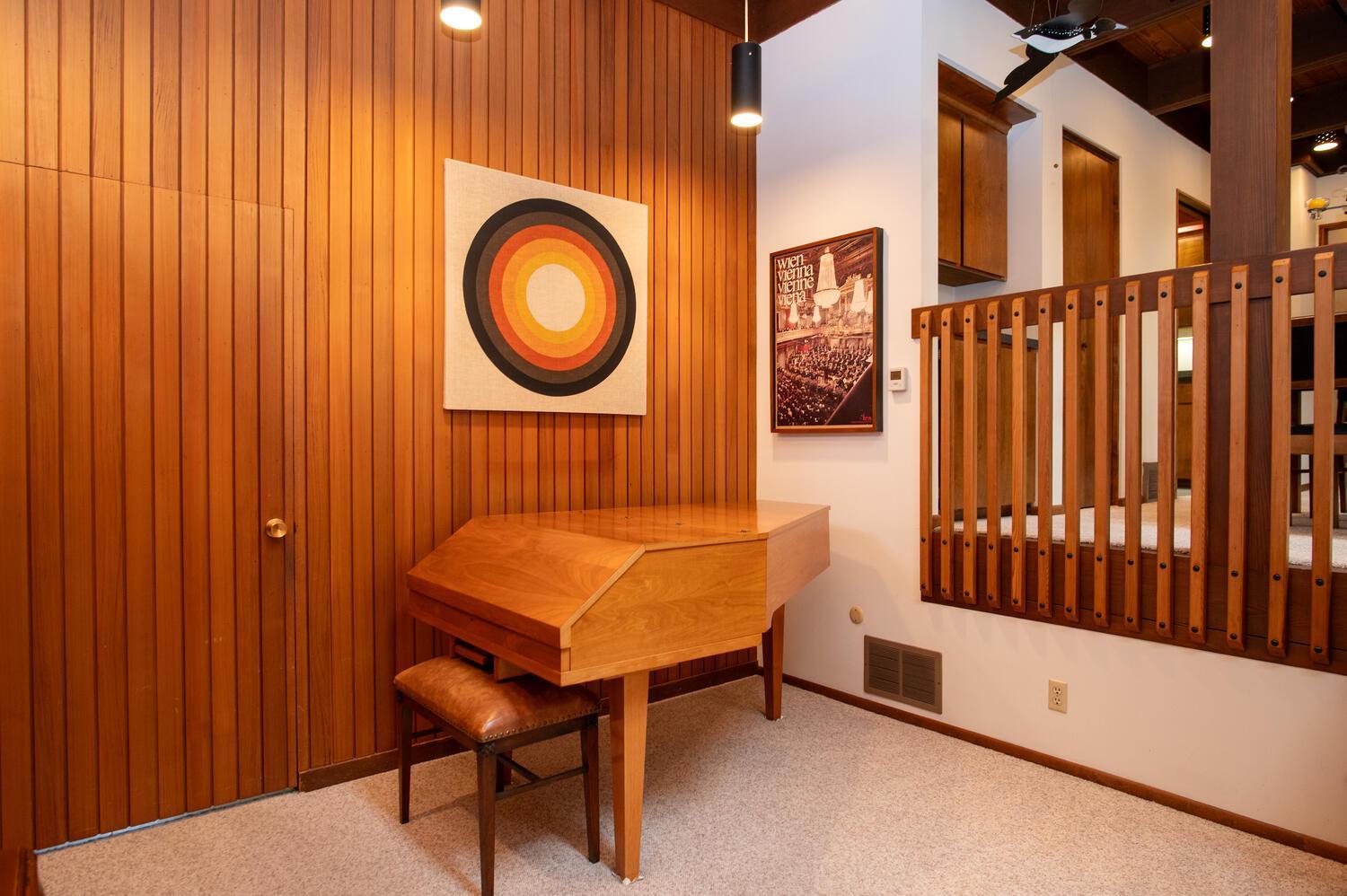 Wood-paneled desk nook with geometric wall art and a wood-railed loft opening.