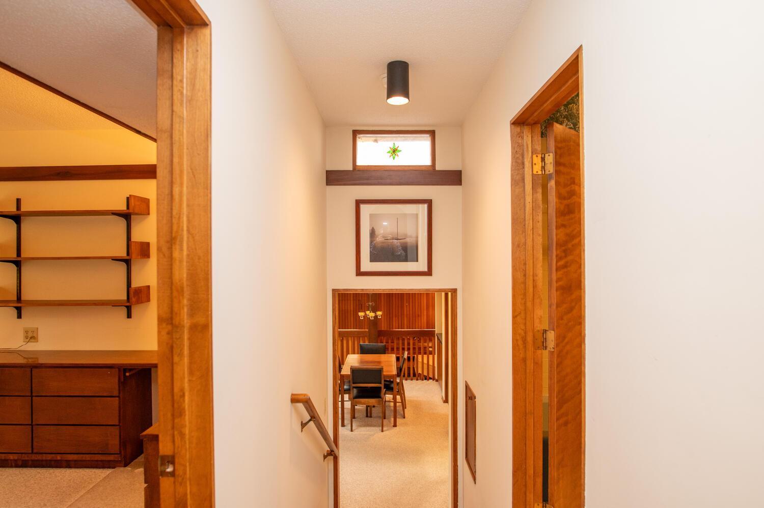 Wood-trimmed hallway overlooks a dining area, with built-in shelving and drawers to the left.