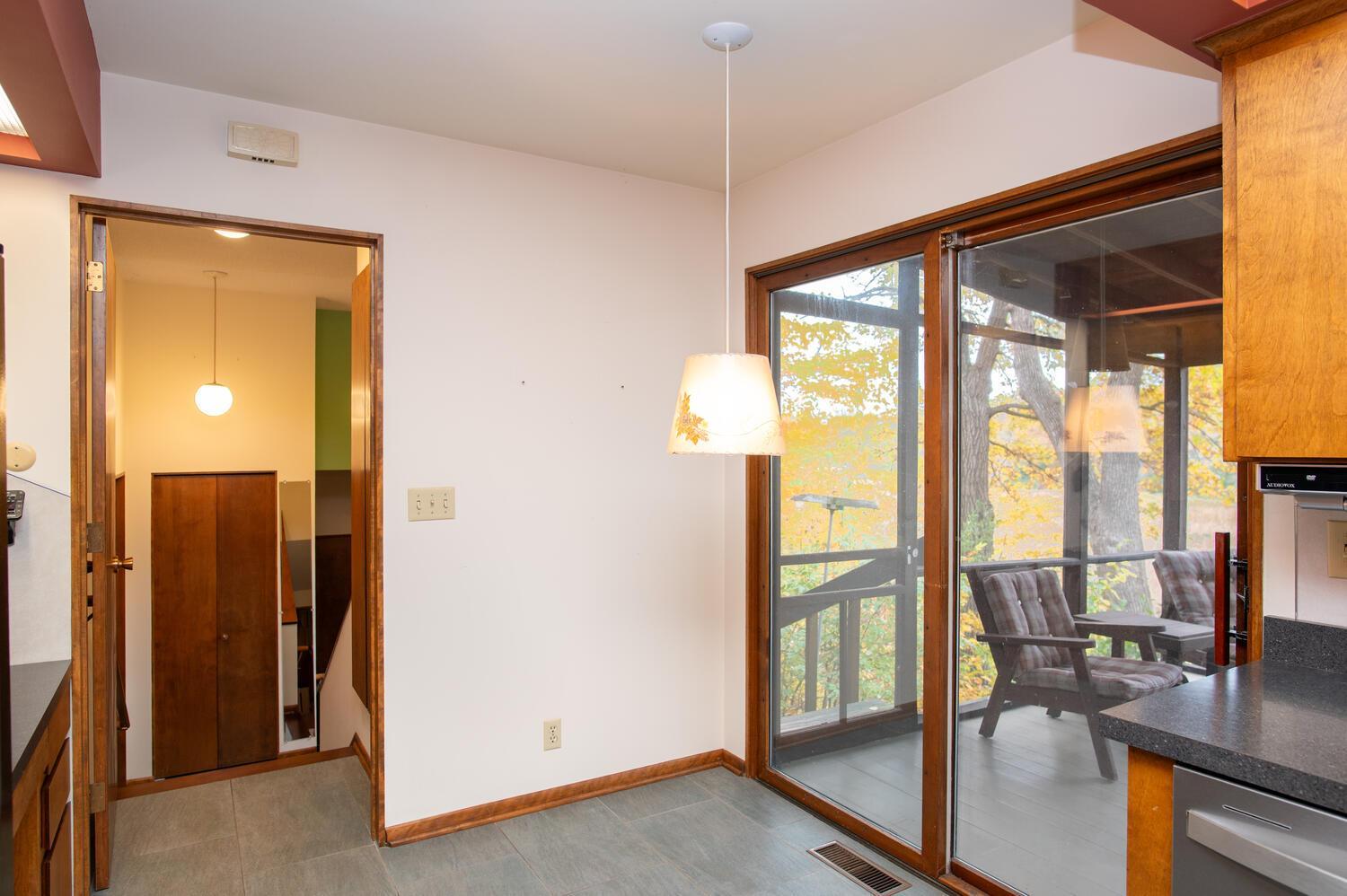 Kitchen with sliding glass doors to a screened porch and autumn trees beyond.