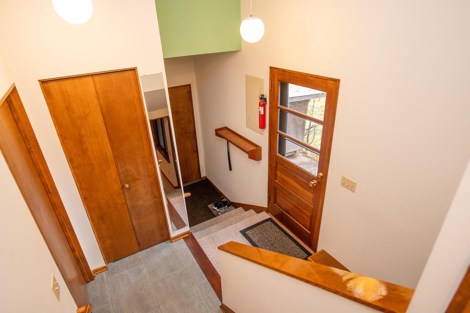 Entryway with gray tile, warm wood doors, a glass-paneled exterior door, and stairs.