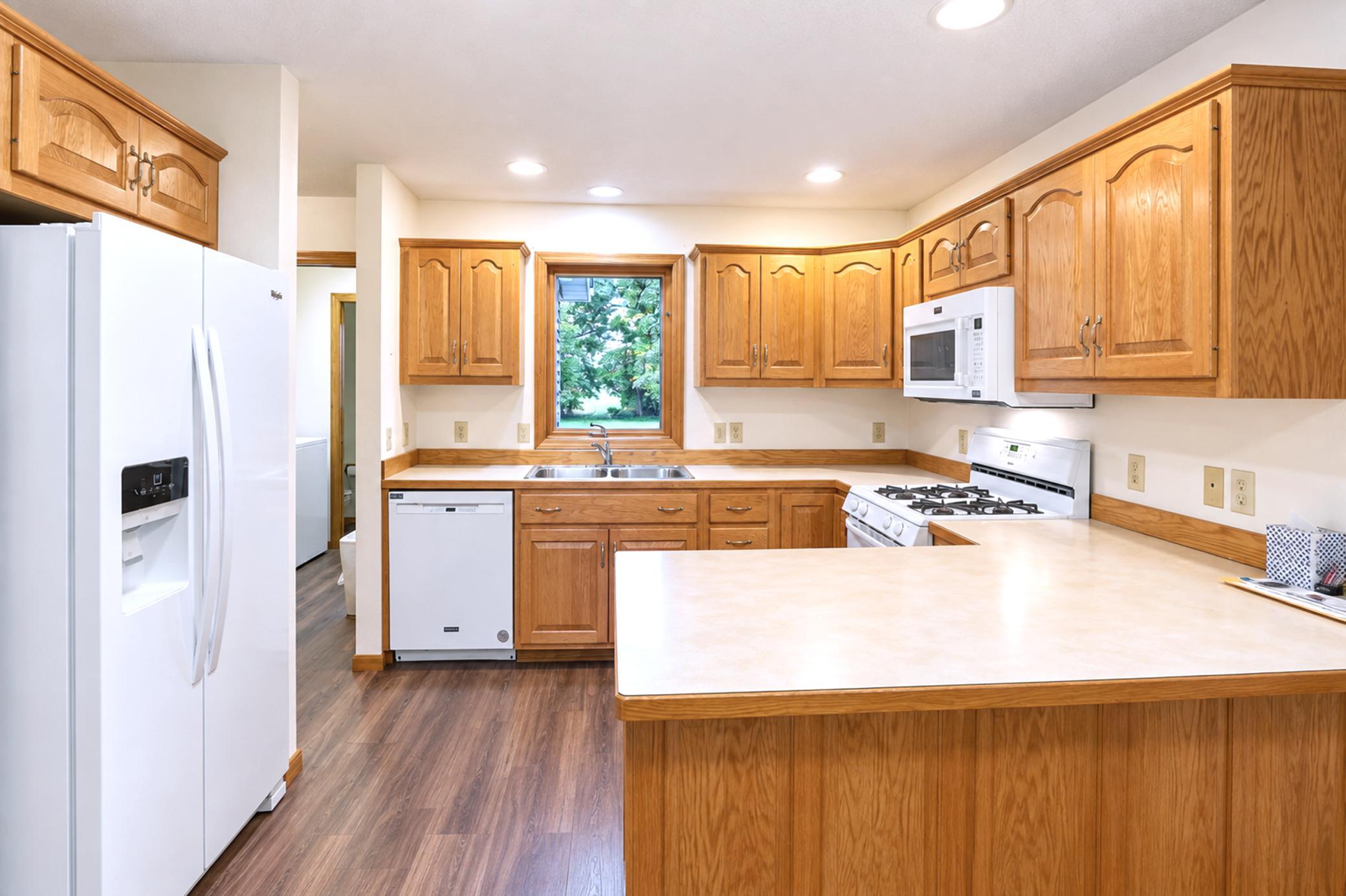 Kitchen with honey-colored wood cabinets, white appliances, and a peninsula counter.