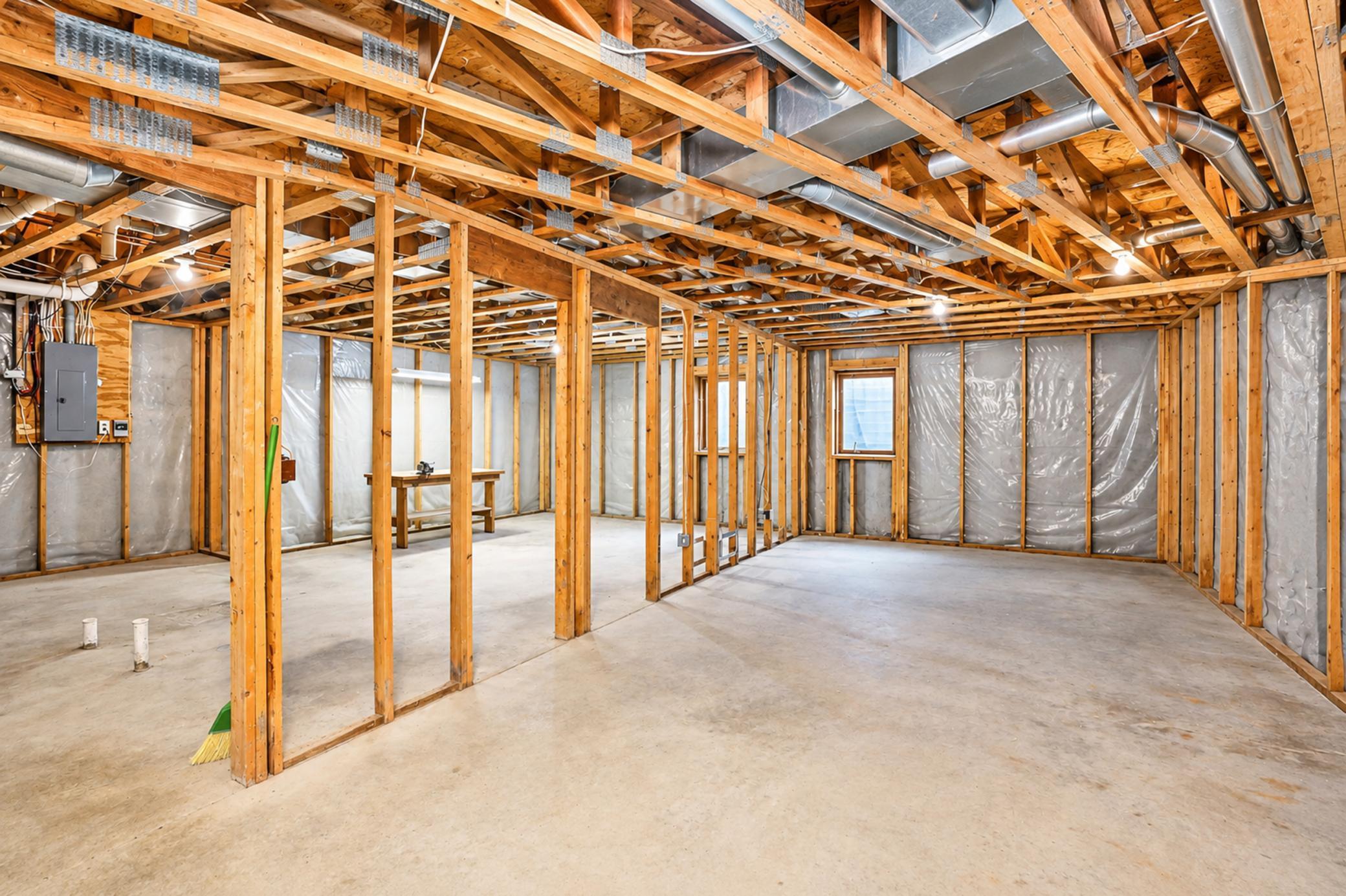 Unfinished basement with exposed framing, concrete floor, and overhead ductwork.