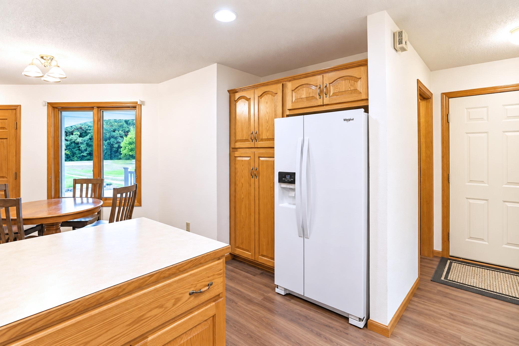 Kitchen with wood cabinetry, a white refrigerator, and a dining table by a window.
