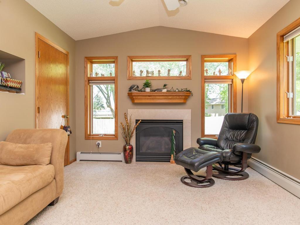 Living room with a fireplace, tall wood-trimmed windows, and a leather recliner with ottoman.