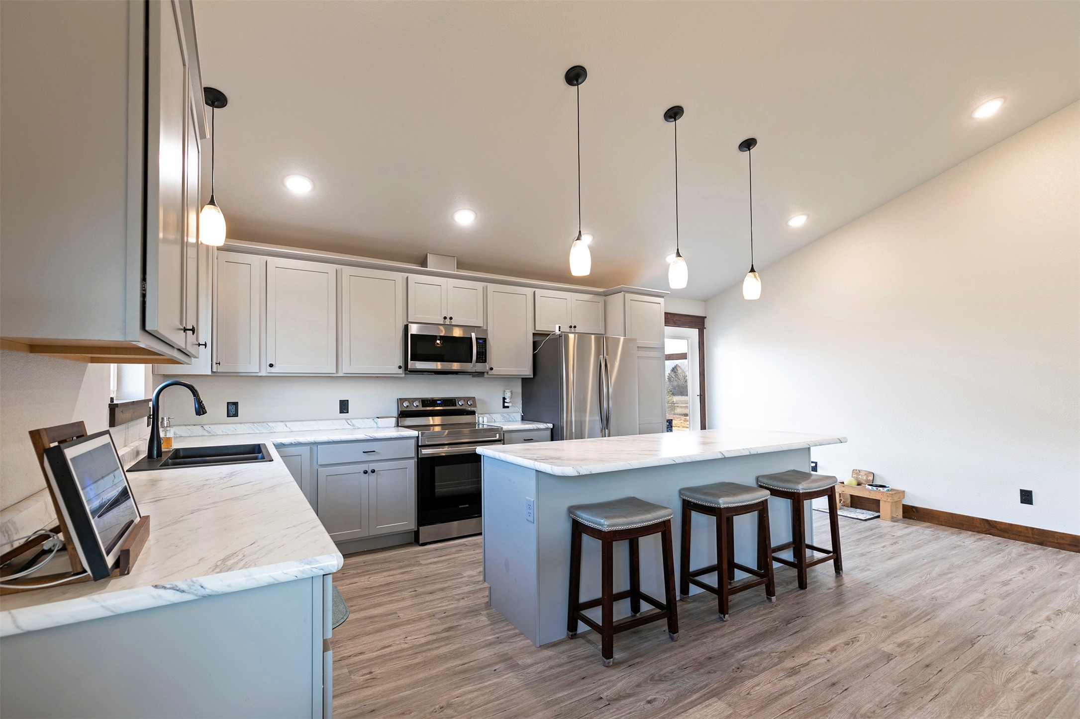 Modern kitchen with white cabinets, stainless steel appliances, and a large island with three bar stools.