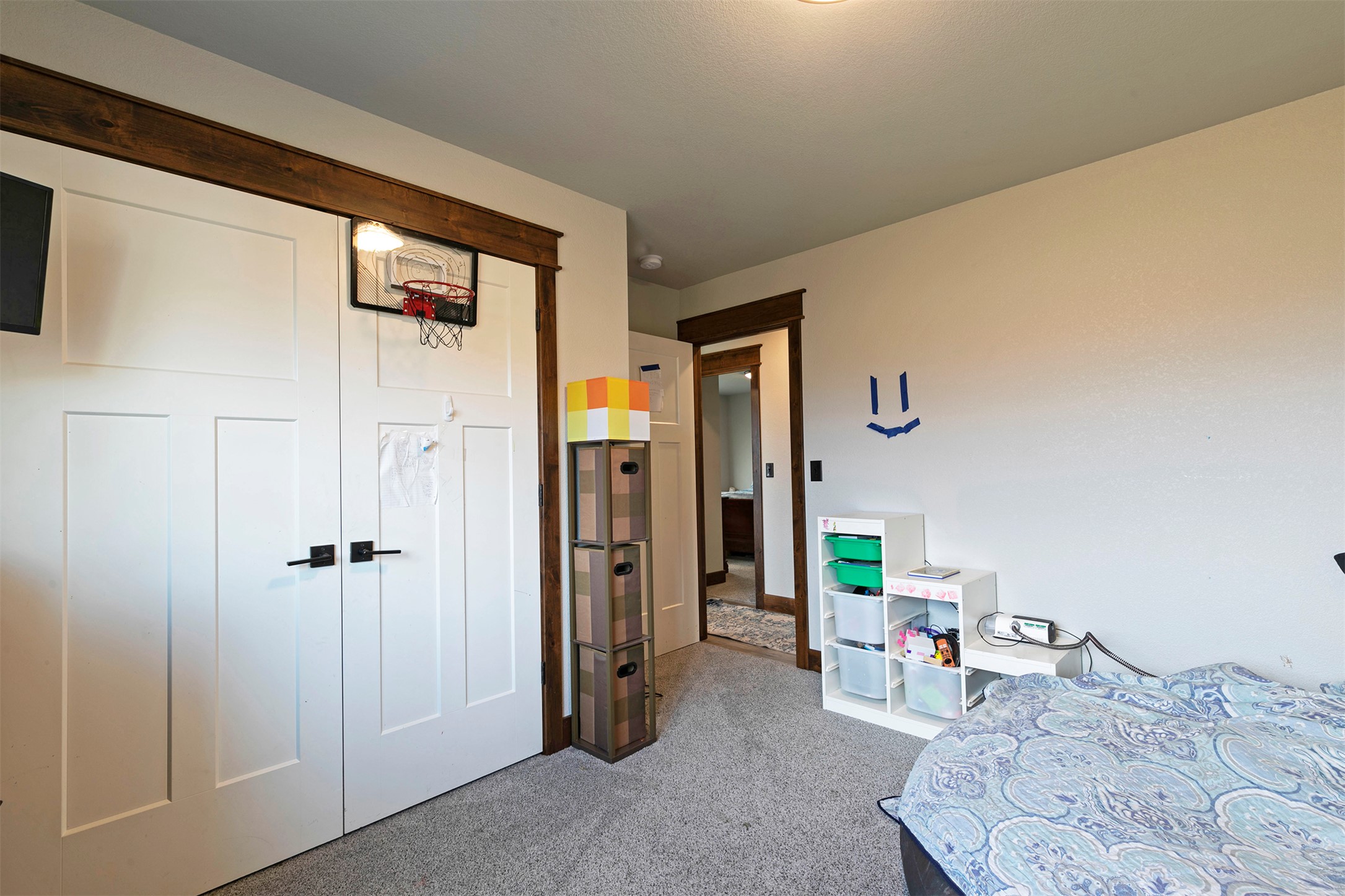 Bedroom with a bed, carpeted floor, and a basketball hoop mounted above the closet doors.