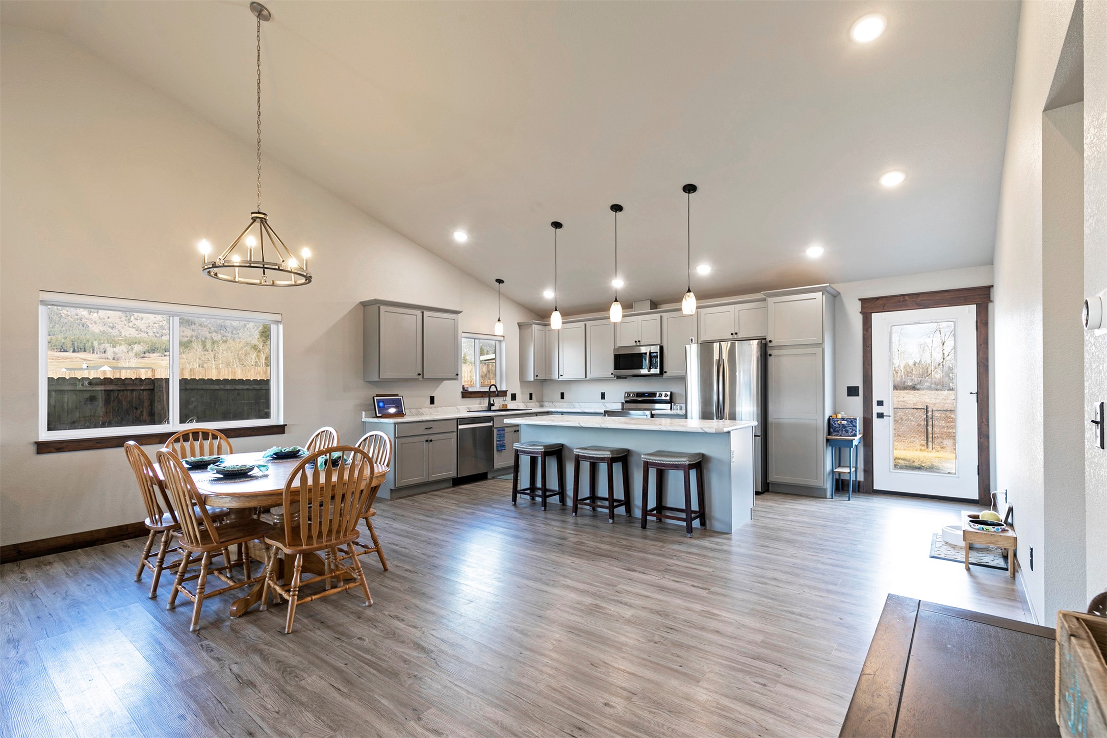 Open kitchen and dining area with a large island, gray cabinets, and a wooden table.