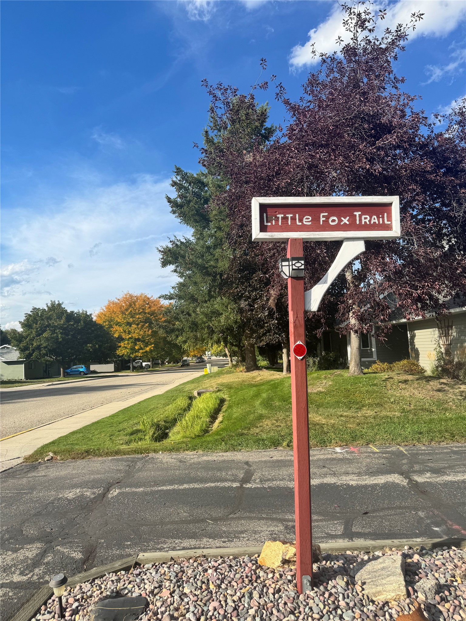 Little Fox Trail street sign beside a tree-lined residential street.