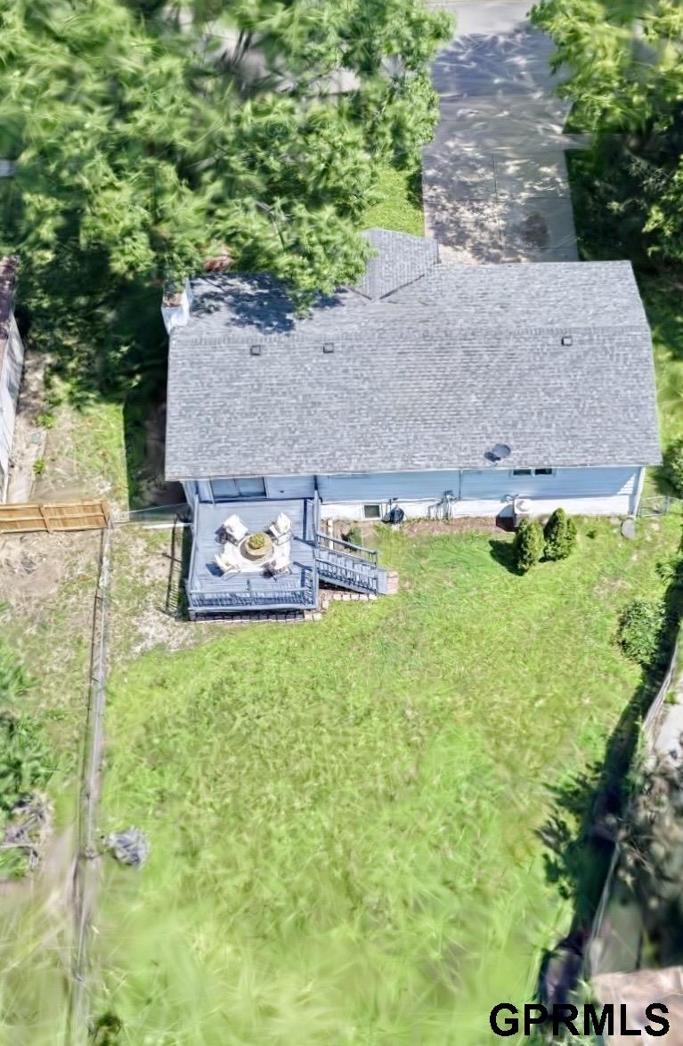 Aerial view of a house with a deck and spacious fenced backyard.