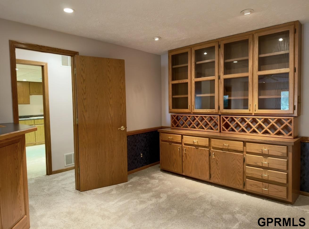 Room with extensive built-in wood cabinetry, glass-front cabinets, and lattice wine storage.