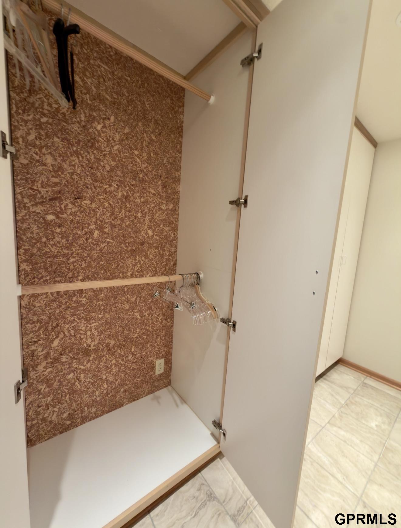 Open built-in closet with wooden hanging rods, clear hangers, and a white shelf.