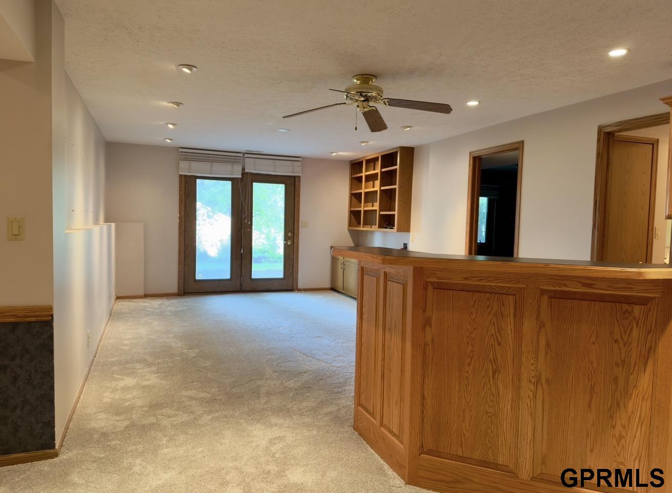 Carpeted living area with a large wood-paneled counter, built-in shelves, and glass patio doors.