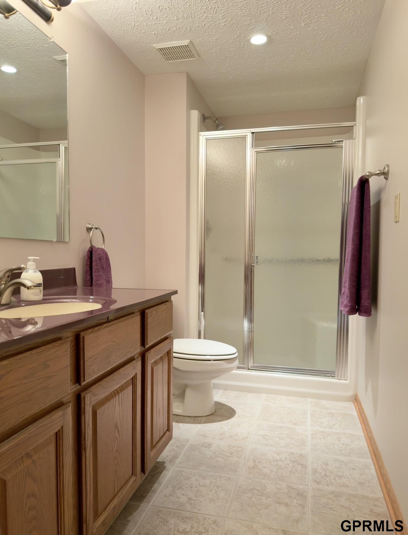 Bathroom with a wood vanity and frosted-glass sliding shower doors.