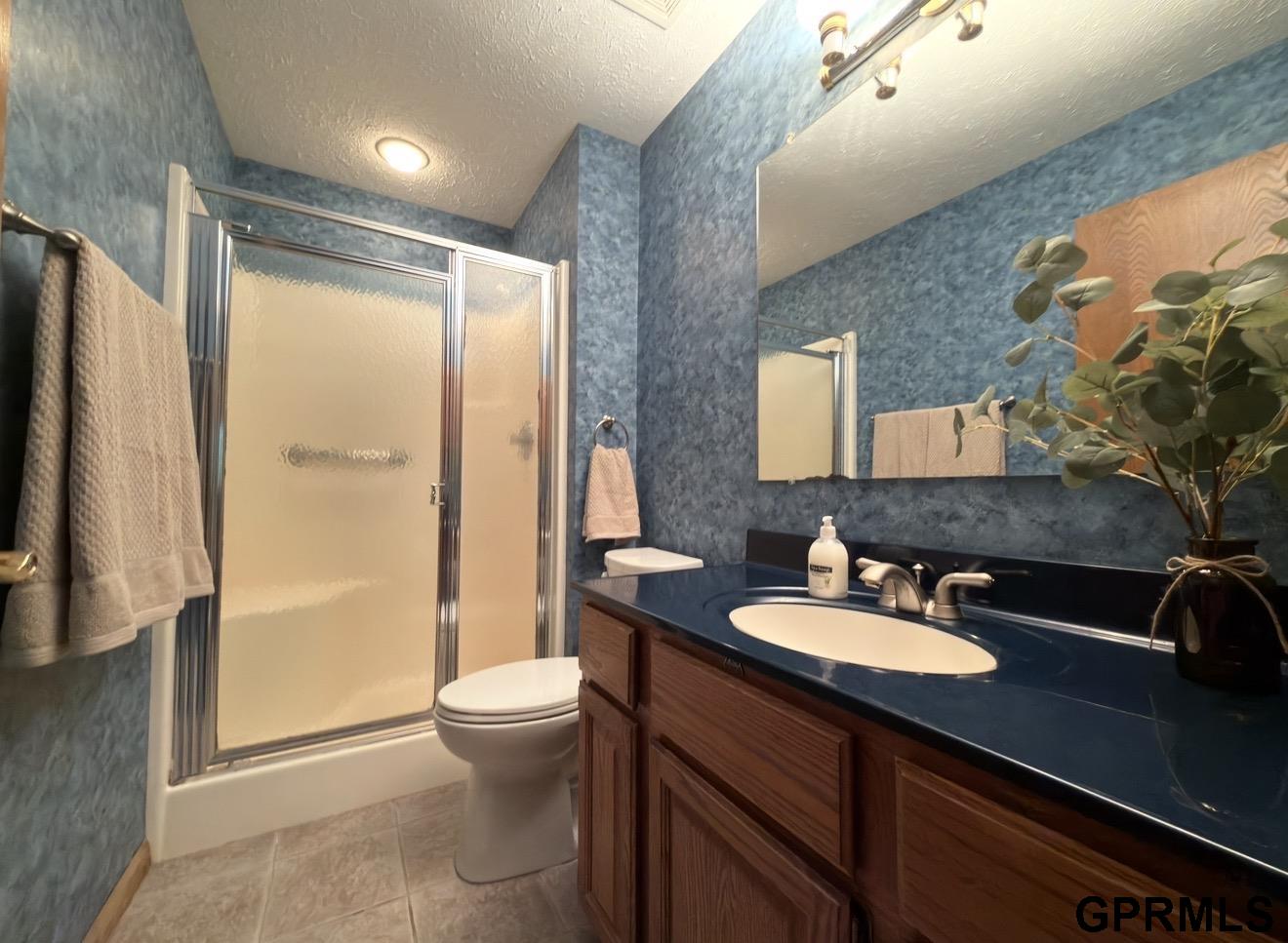 Bathroom with blue walls, frosted-glass shower, and dark blue vanity countertop.
