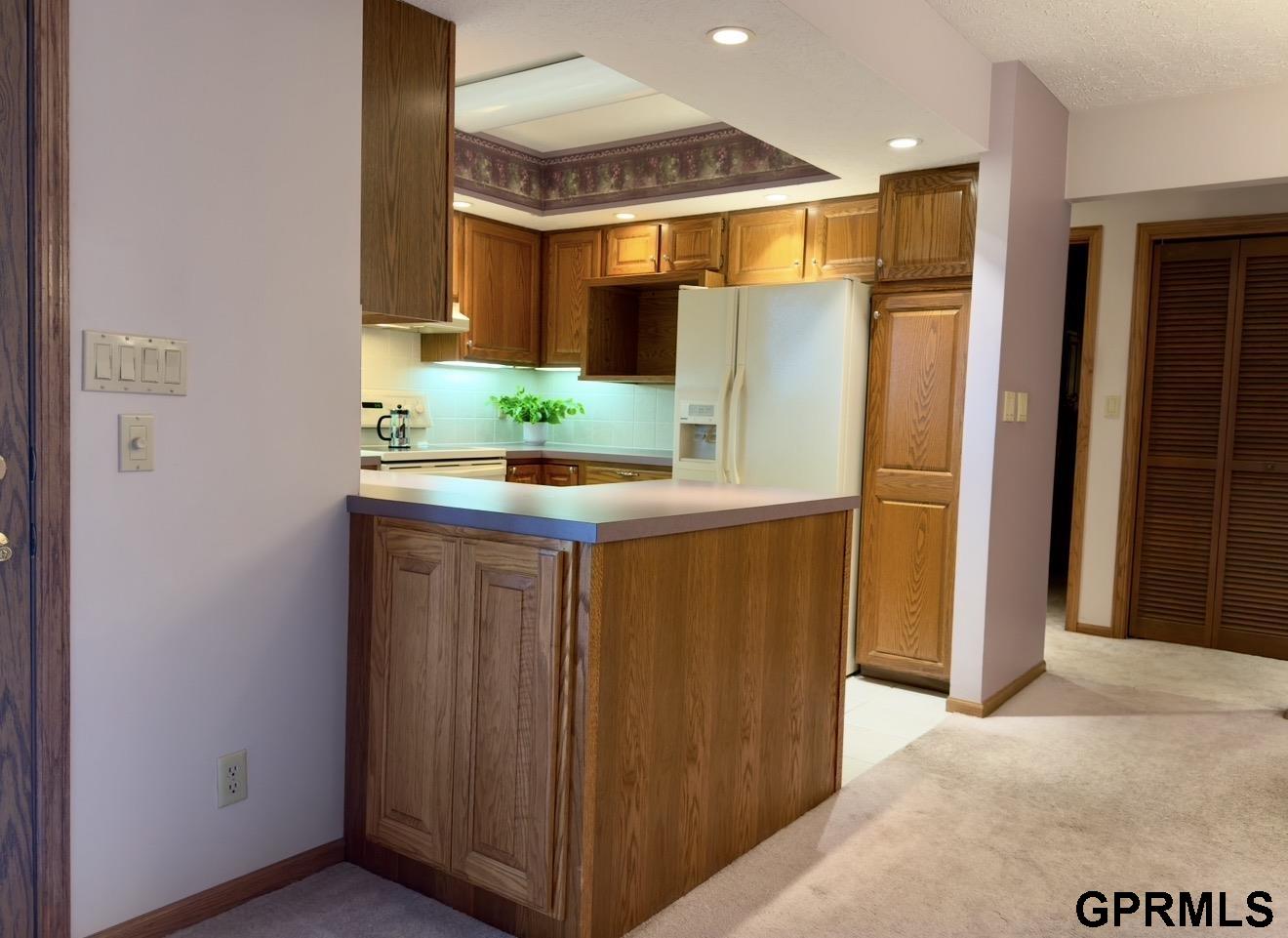 Kitchen with oak cabinetry, white appliances, and a peninsula breakfast bar.