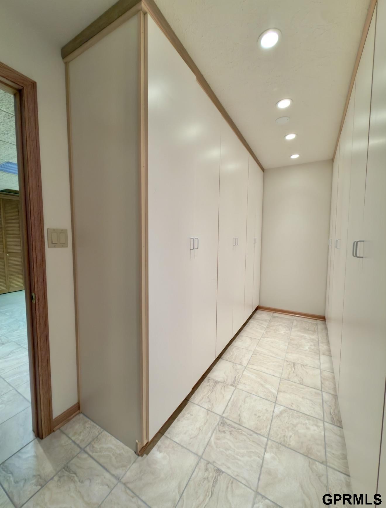 Interior corridor lined with white built-in cabinets and light tiled flooring.