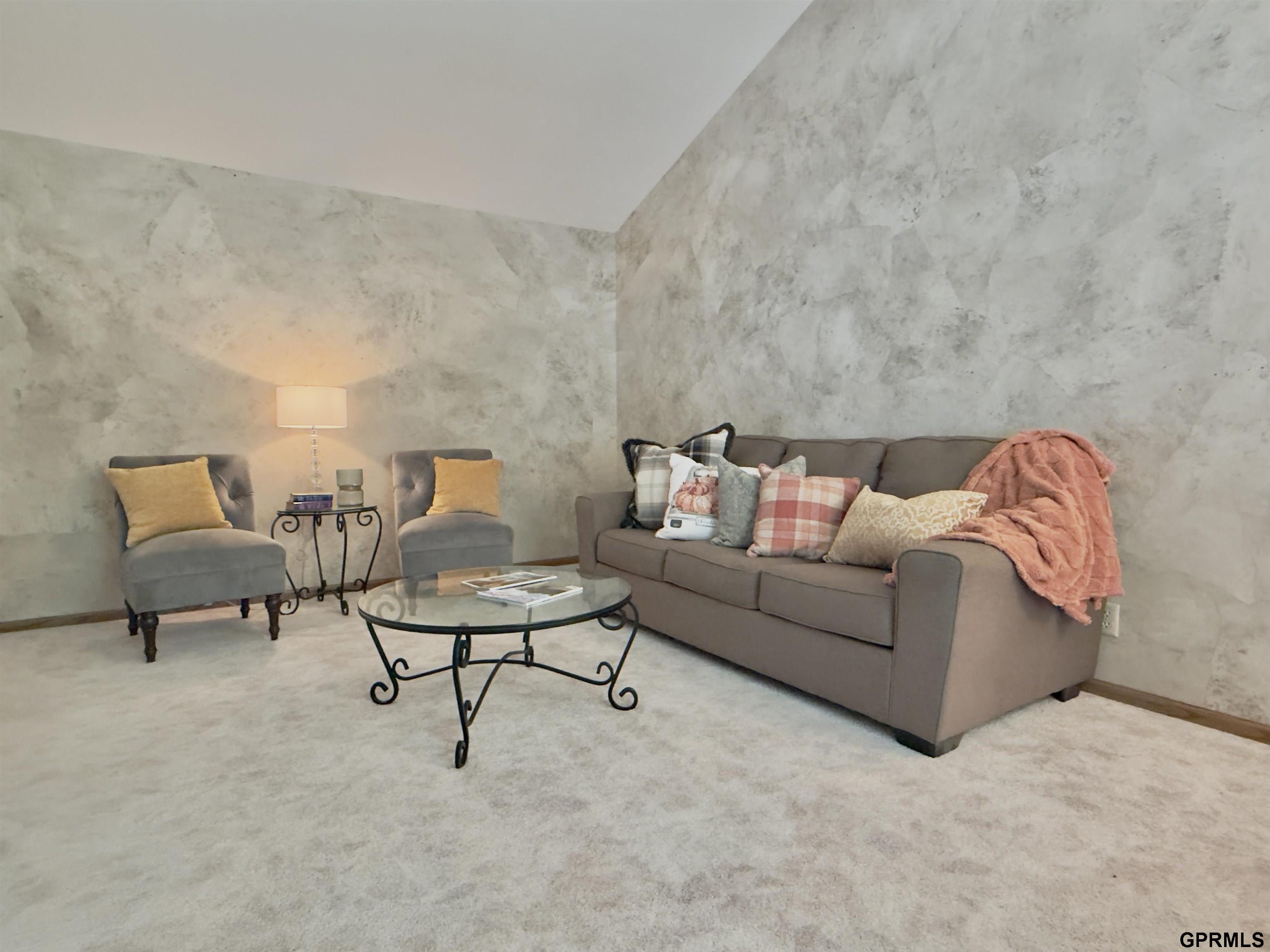 Staged living room with a taupe sofa, gray armchairs, and glass-topped tables.
