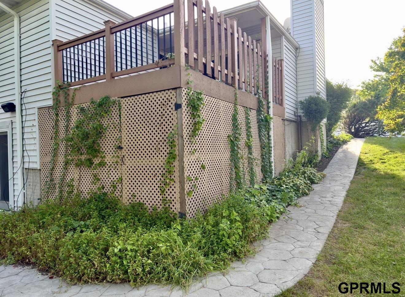 Raised wooden deck with lattice skirting beside a curved stone walkway and garden.