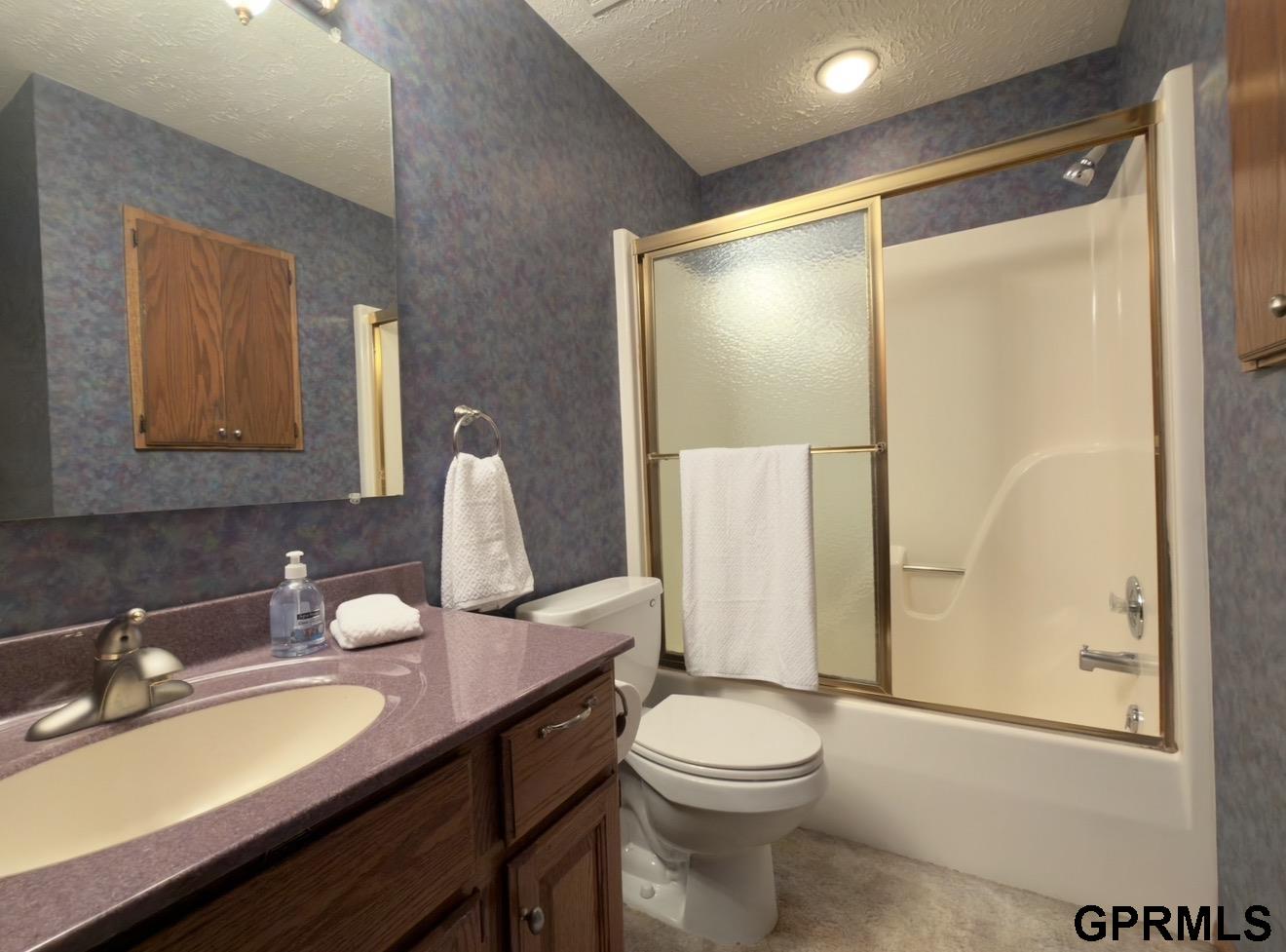 Bathroom with a purple vanity countertop and a tub-shower with frosted-glass sliding doors.