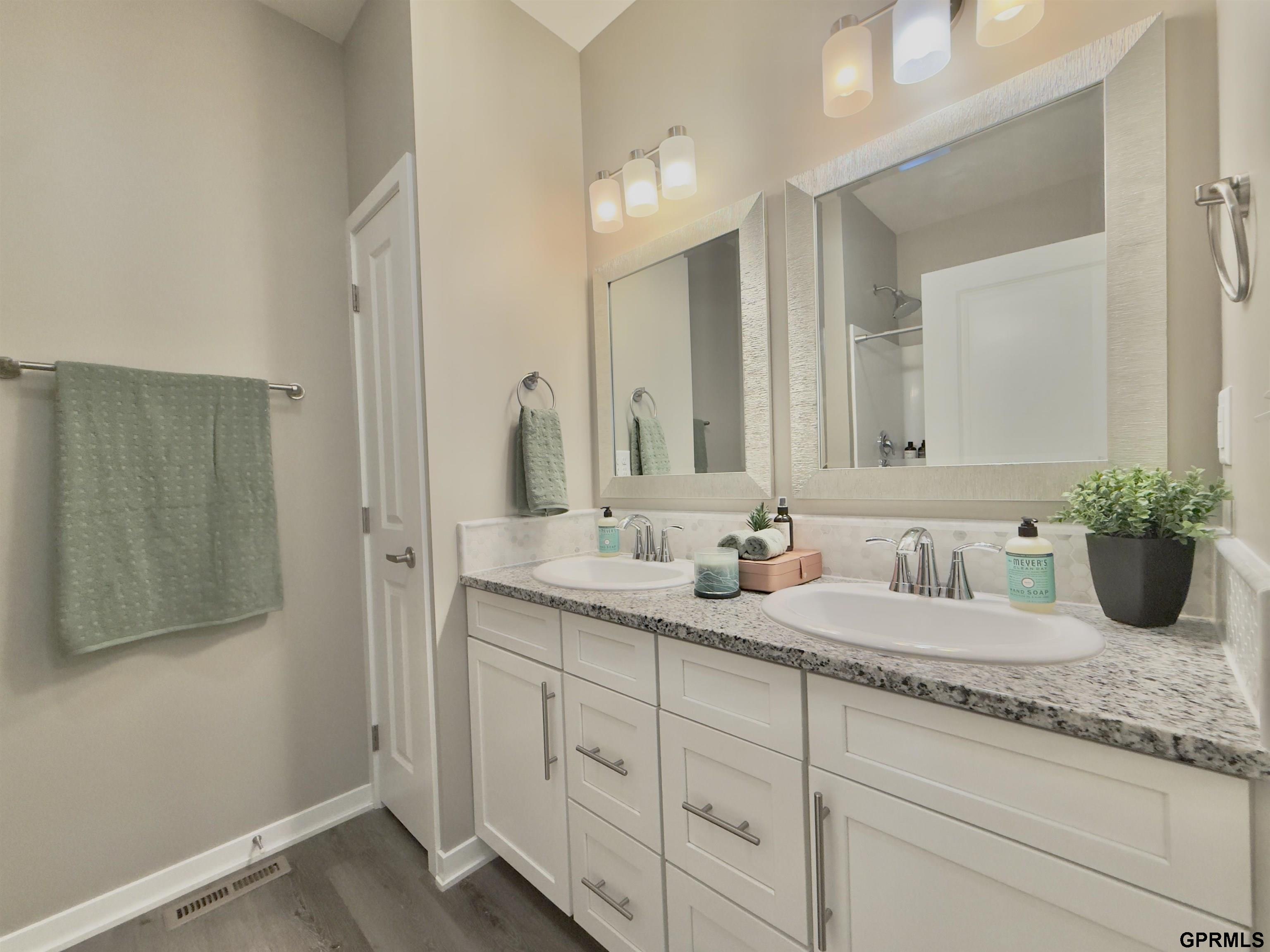 Bathroom with a double-sink white vanity, granite countertop, and two large framed mirrors.