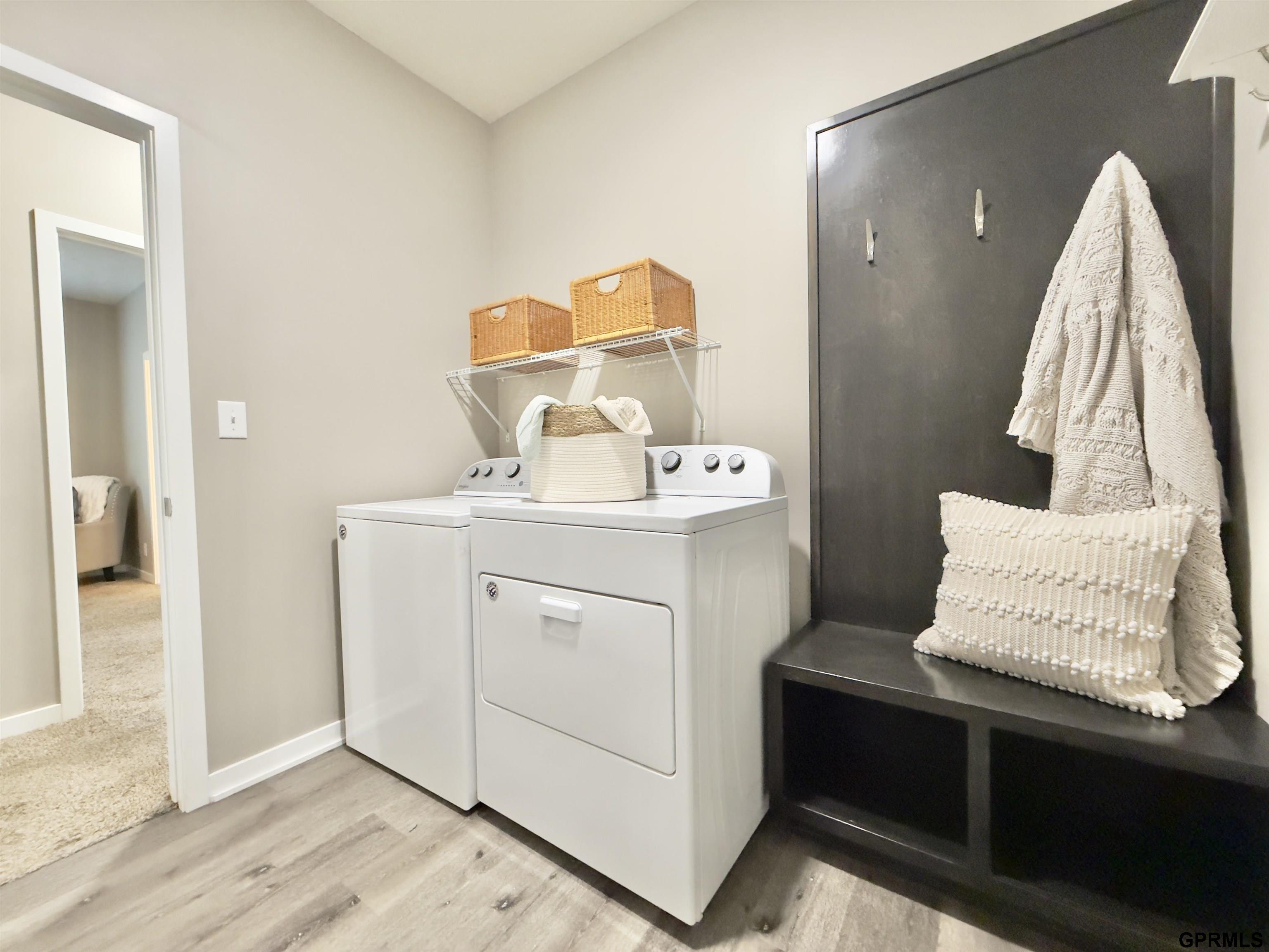 Laundry room with white washer and dryer beside a dark built-in bench.