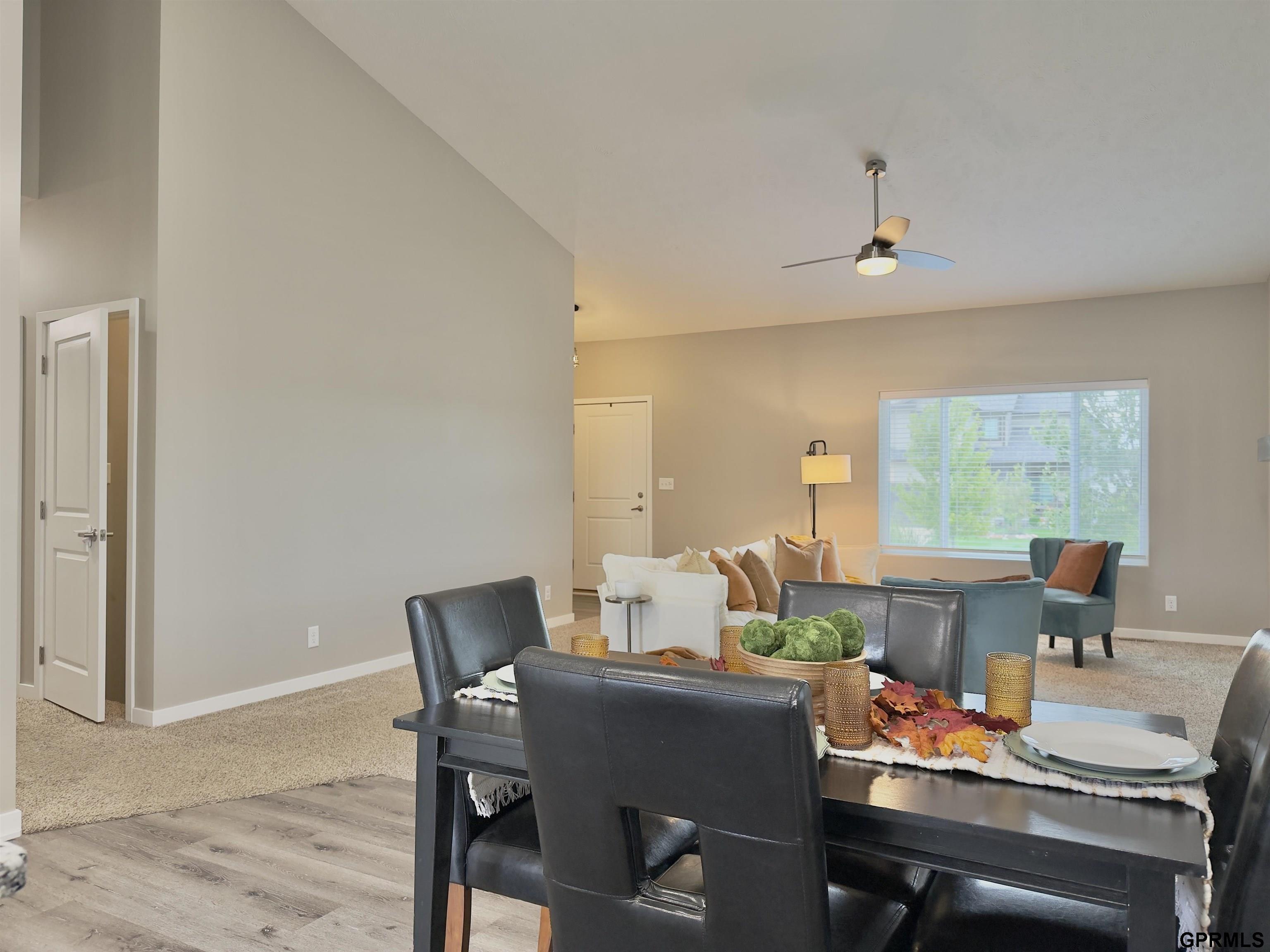 Dining area opens to a furnished living room with a large window and high ceiling.