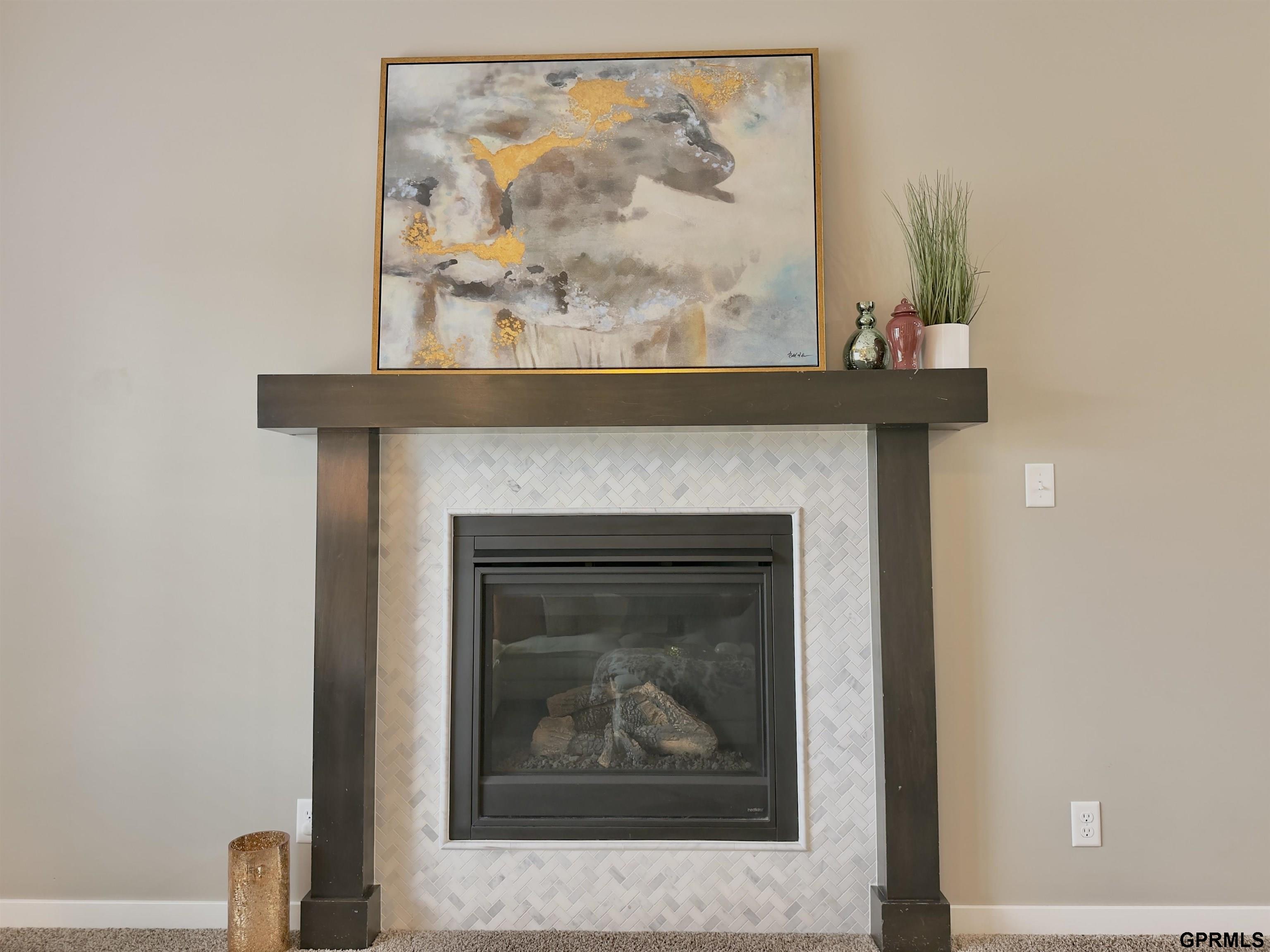 Living room fireplace with a dark wood mantel and white herringbone tile surround.