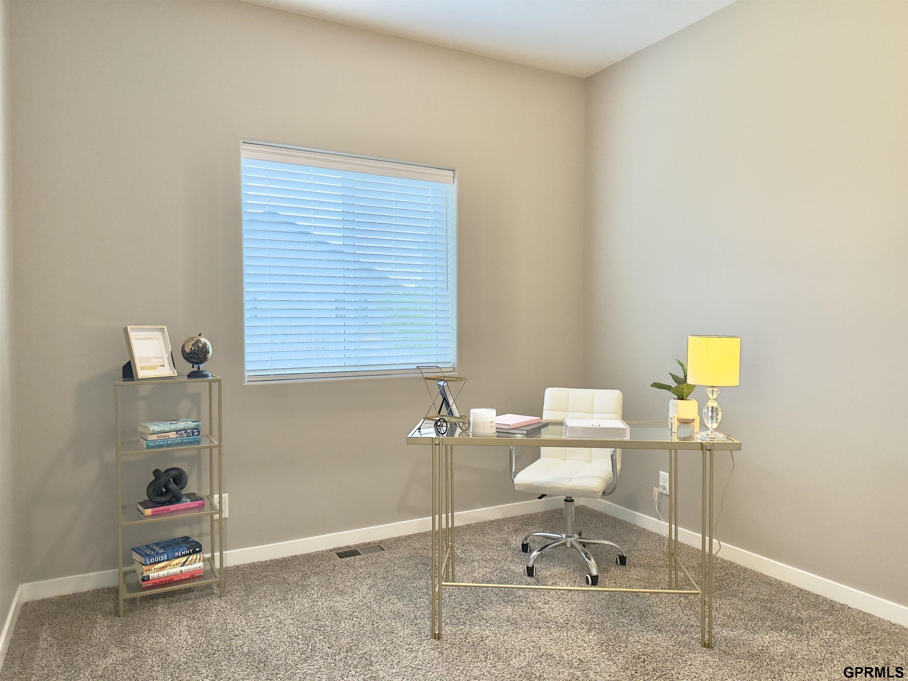 Staged home office with a glass desk, white chair, and window with blinds.