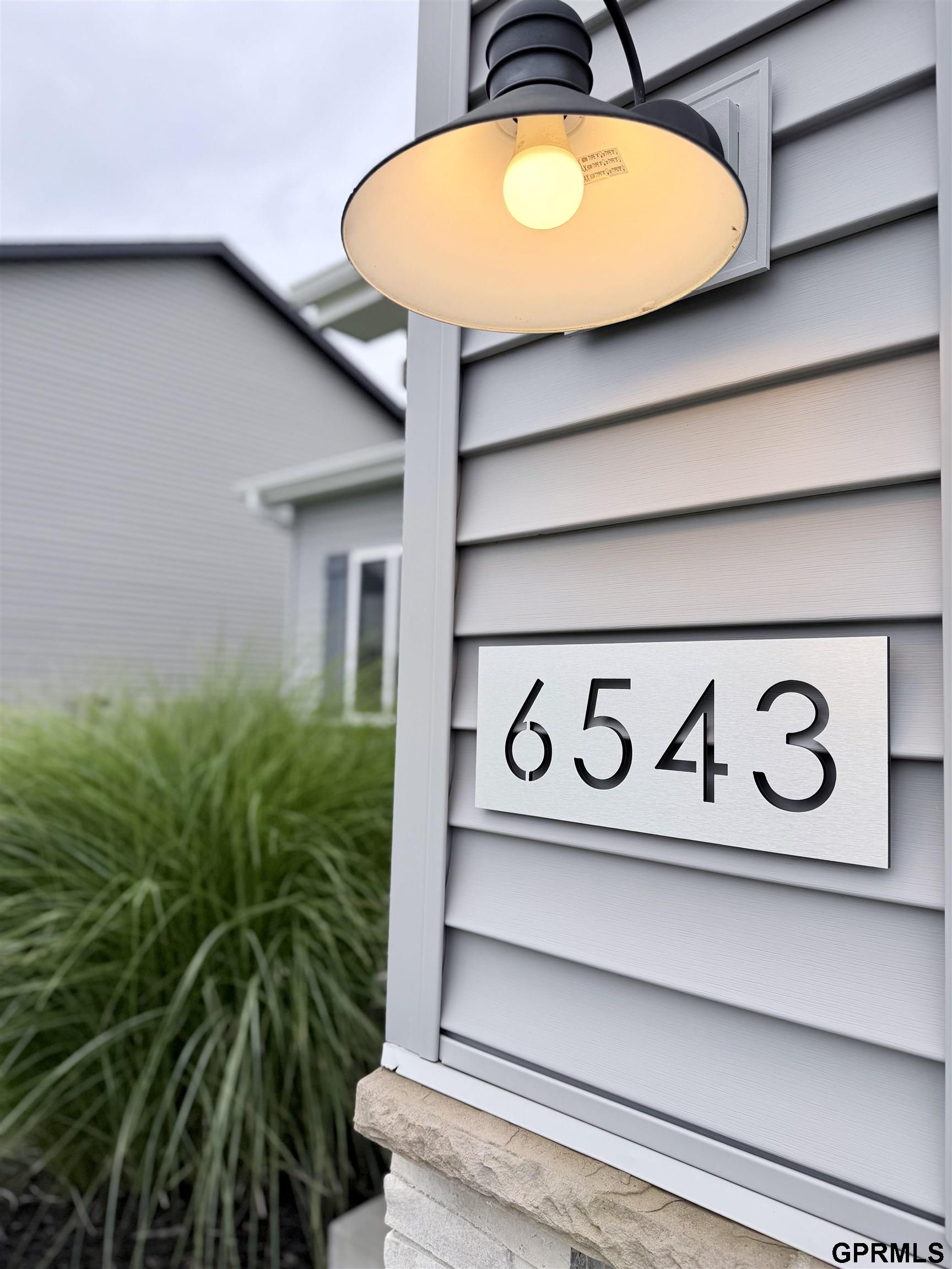 House exterior with a lit porch light above a metal address plaque reading 6543.