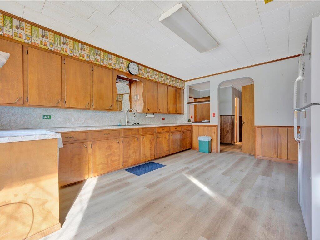 Kitchen with honey-colored cabinets, a light wood-look floor, and an arched doorway.