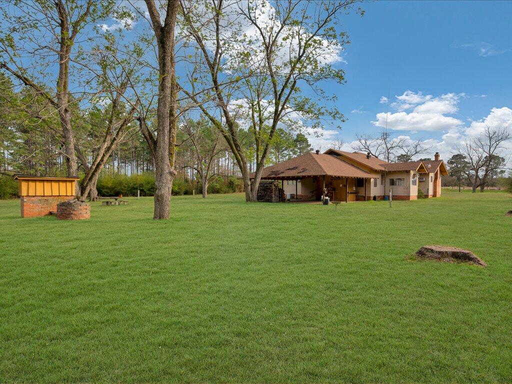 Single-story brick house with a covered porch, broad lawn, and mature trees.